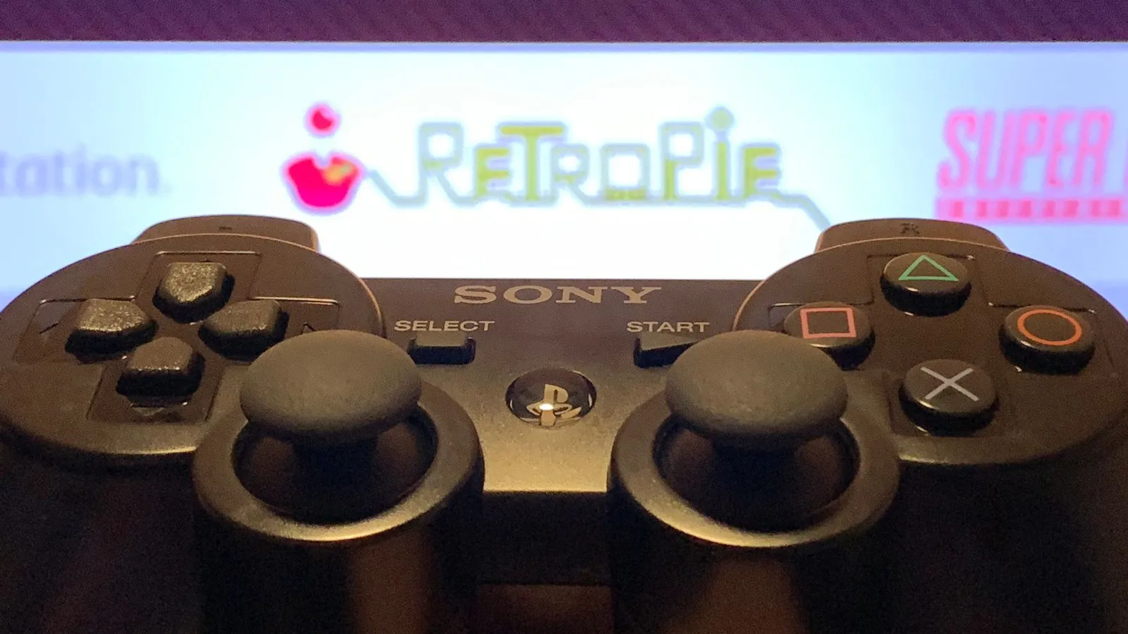 Bộ điều khiển PS3 đặt cạnh màn hình hiển thị giao diện RetroPie, sẵn sàng cho trải nghiệm game retro.