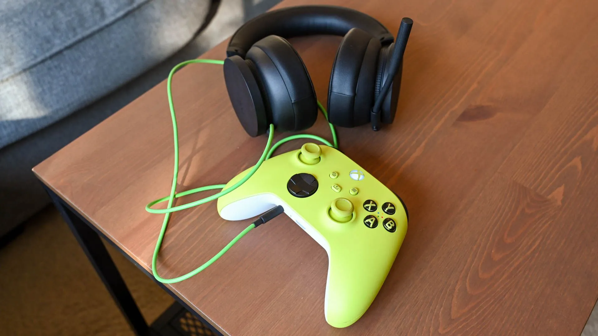 Bộ điều khiển Xbox Series X và một chiếc tai nghe chơi game được đặt trên bàn, thể hiện nhu cầu về thiết bị âm thanh khi chơi trực tuyến.