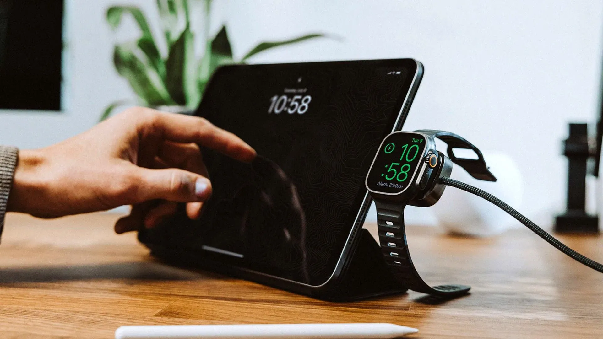 Cáp sạc đa năng Nomad Universal Cable dành cho Apple Watch và thiết bị USB-C đang được sử dụng cùng với một máy tính bảng.