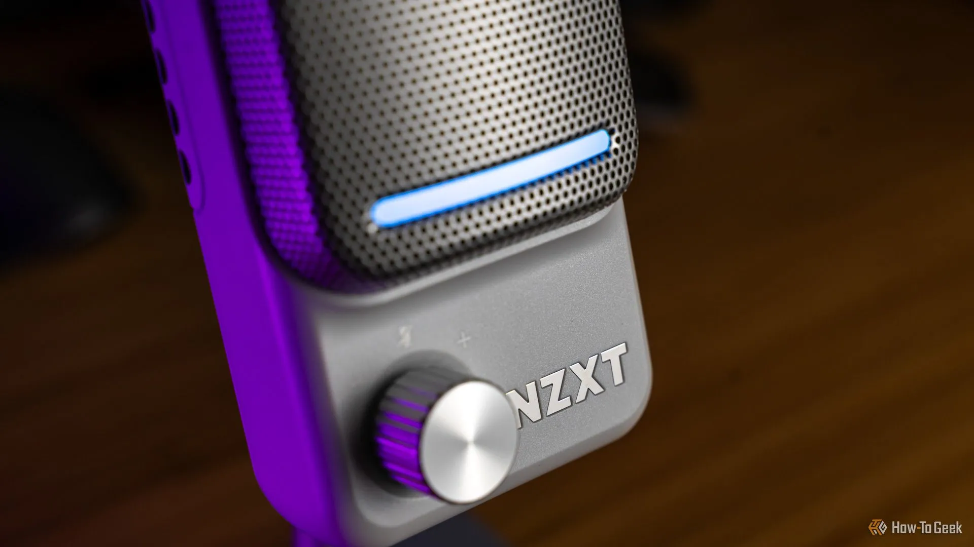 Chụp cận cảnh mặt bên của microphone gaming NZXT Capsule Elite màu đen, hiển thị núm điều chỉnh gain và dải đèn LED, nhấn mạnh thiết kế hiện đại và chuyên nghiệp.