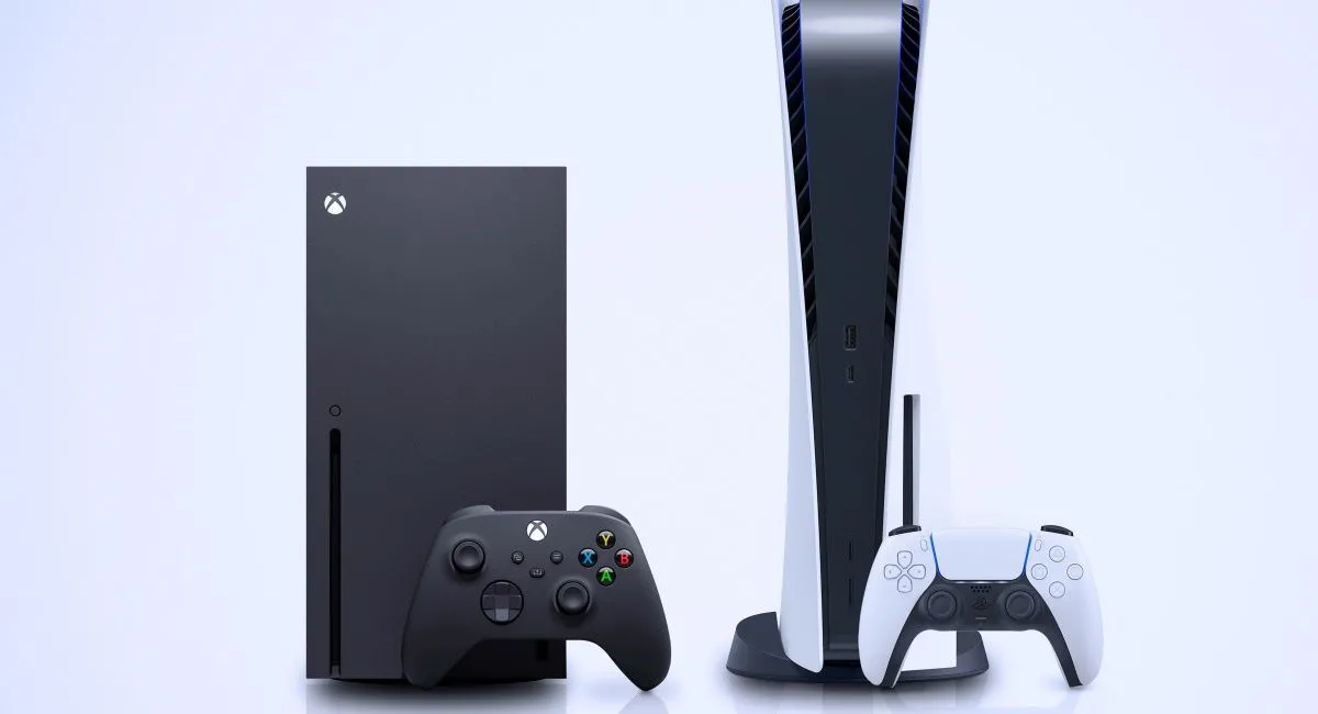 Hai chiếc console game hiện đại: Xbox Series X màu đen và PlayStation 5 màu trắng, đặt cạnh nhau trên bề mặt phản chiếu