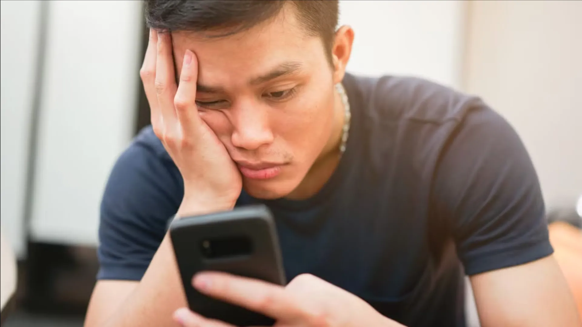 Hình ảnh một người dùng đang lướt điện thoại với vẻ mặt nhàm chán, biểu thị sự mất tập trung hoặc 'doomscrolling'.