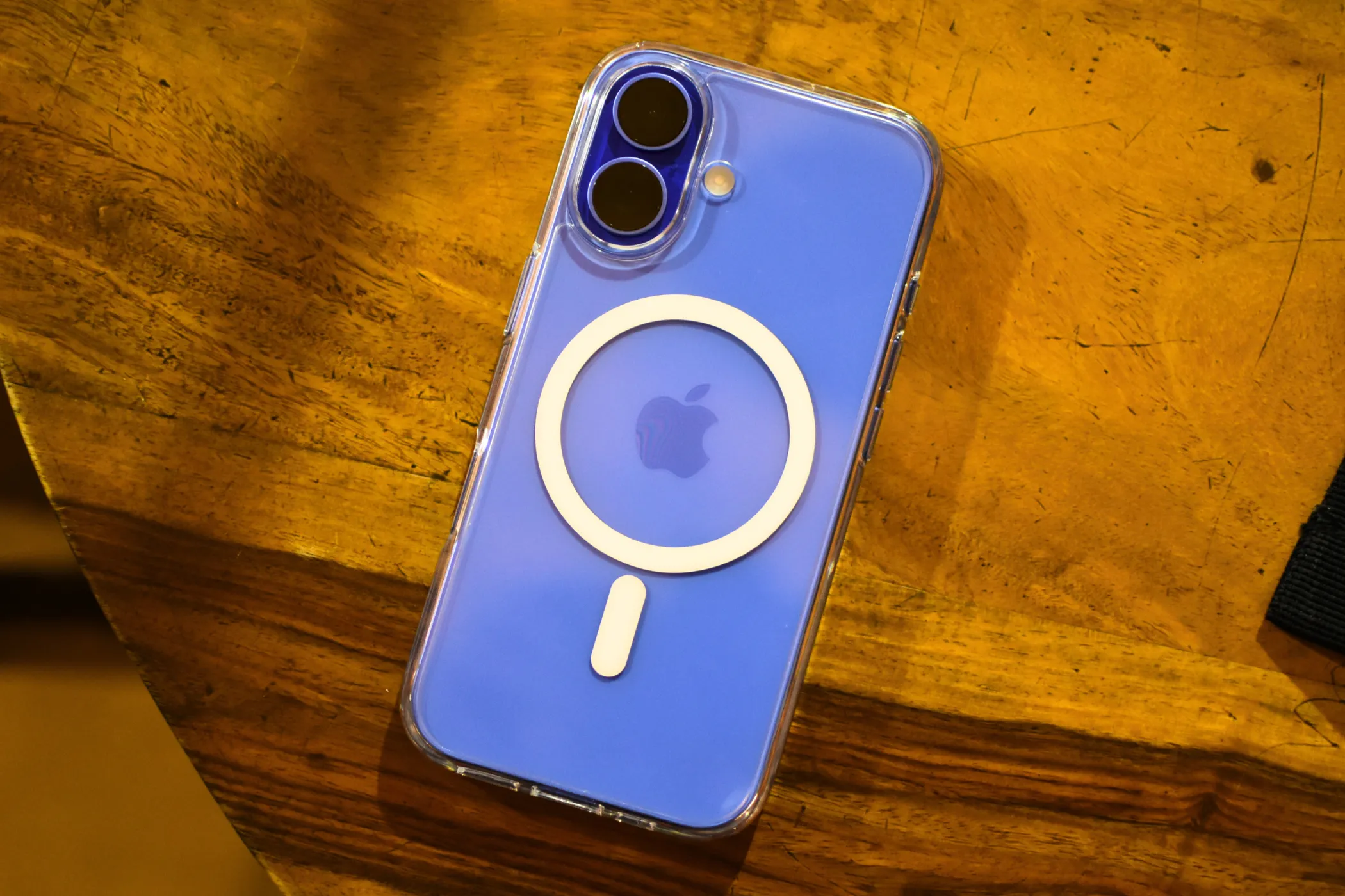 iPhone 16 màu Ultramarine với ốp lưng MagSafe trong suốt, thể hiện thiết kế cụm camera, hỗ trợ các tính năng như khóa nét và phơi sáng.