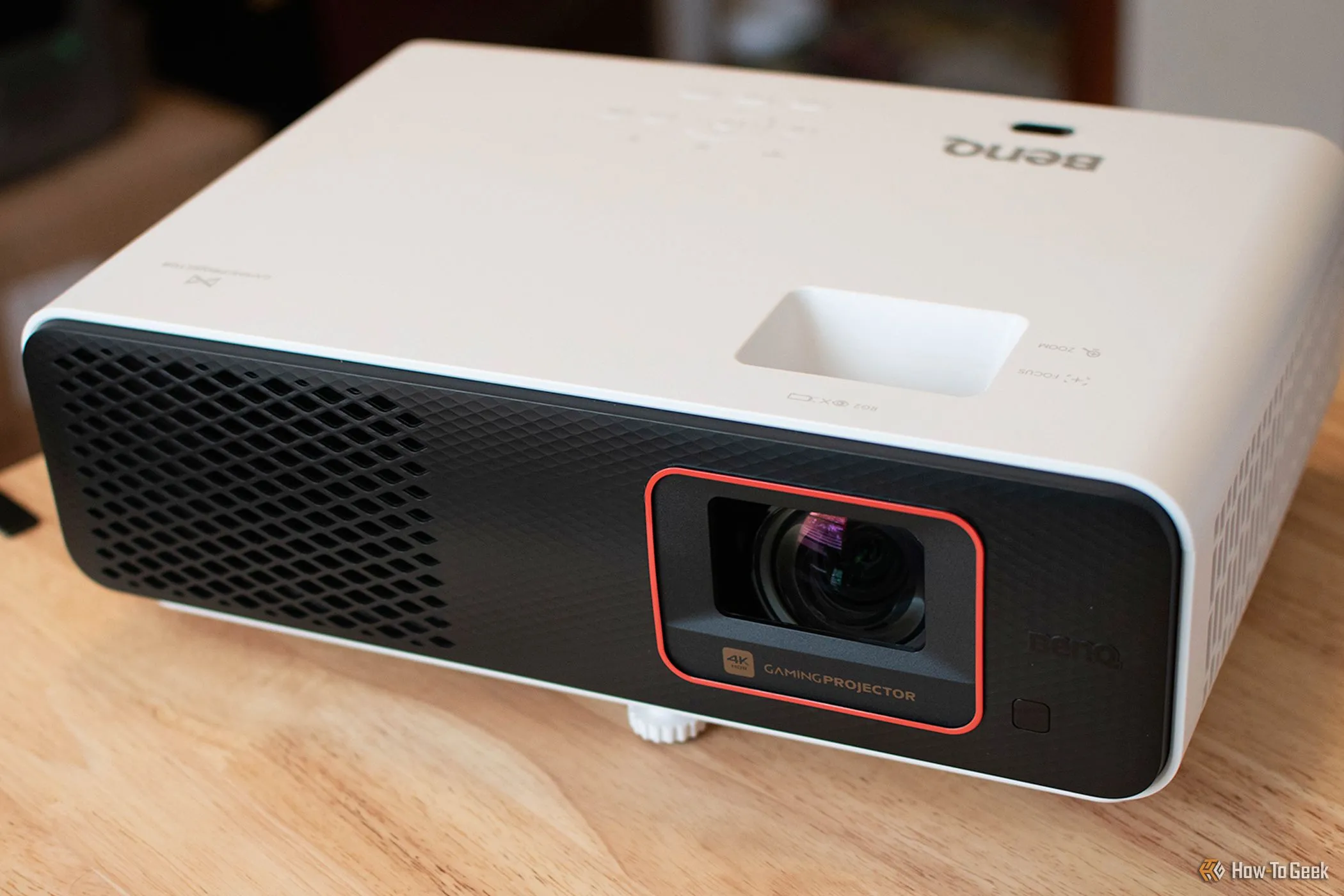 Máy chiếu BenQ X500i Short-Throw đặt trên bàn, cung cấp hình ảnh 4K sắc nét và âm thanh sống động.