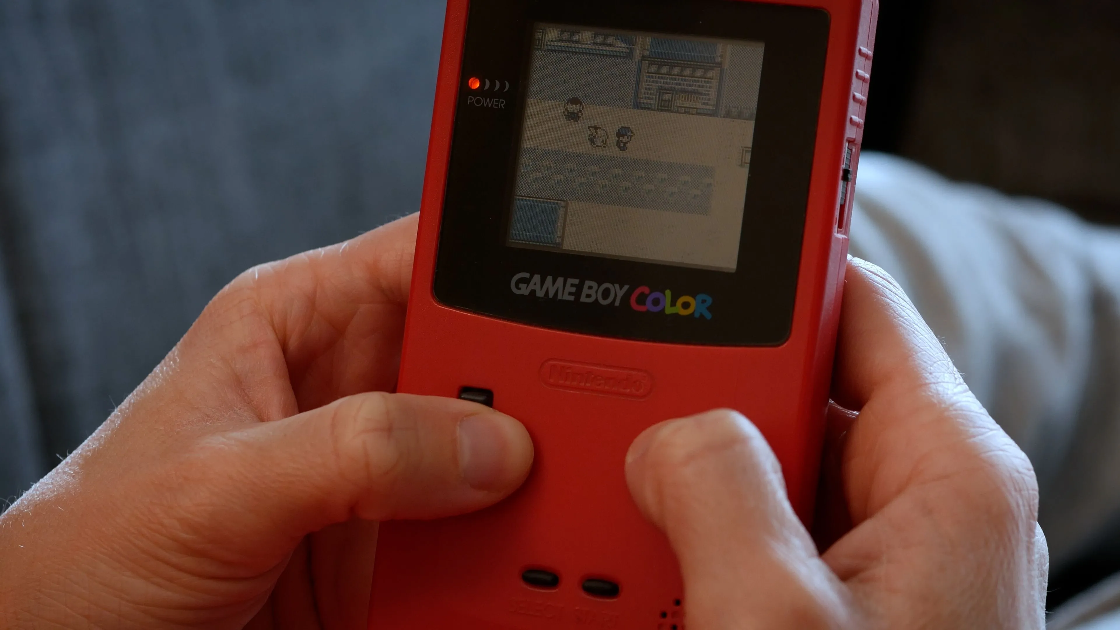 Một người chơi game Pokémon trên máy Game Boy Color, minh họa sự phổ biến của thể loại game nhập vai Pokémon.