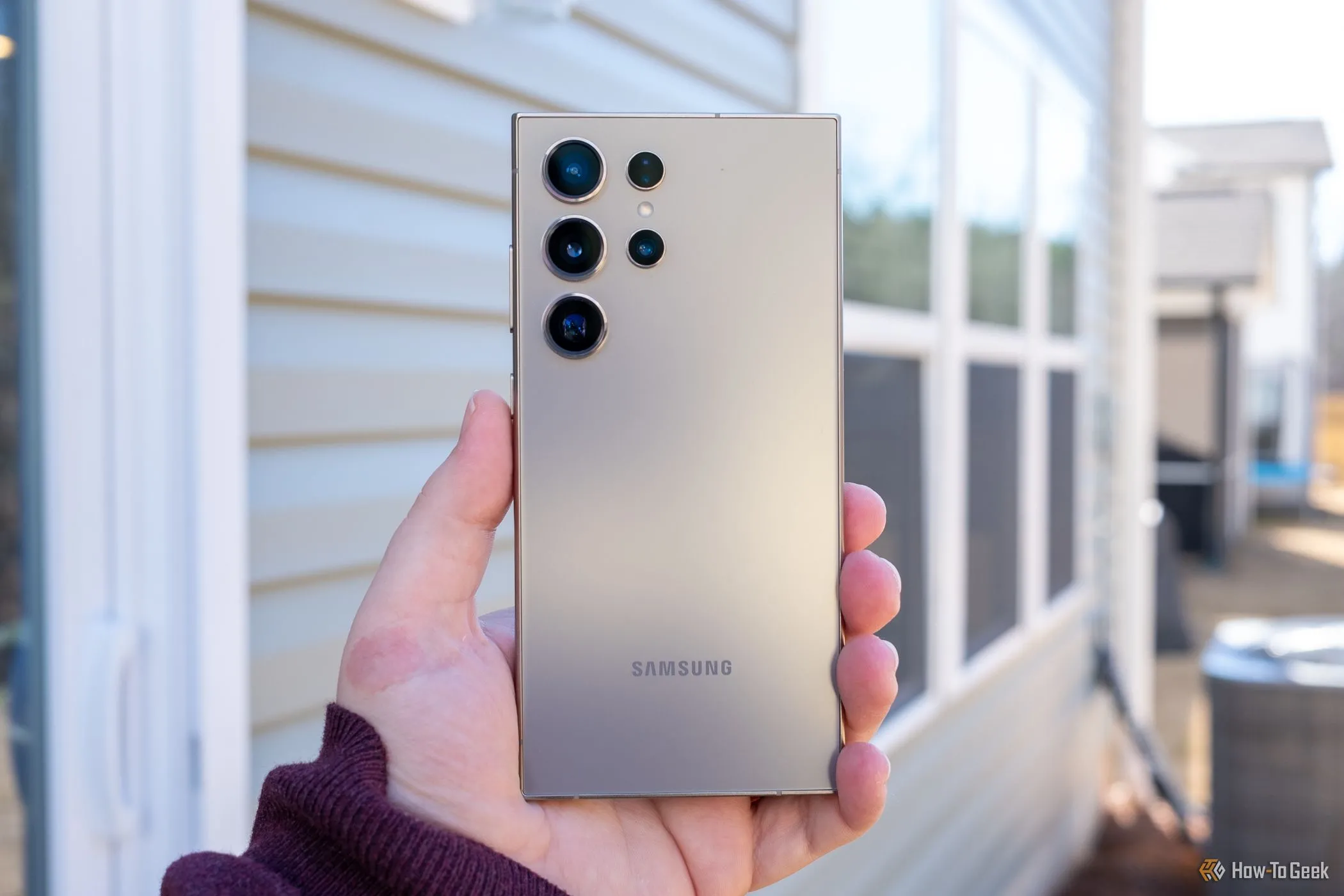 Một người đang cầm điện thoại Samsung Galaxy S24 Ultra màu xám titan, khoe mặt lưng