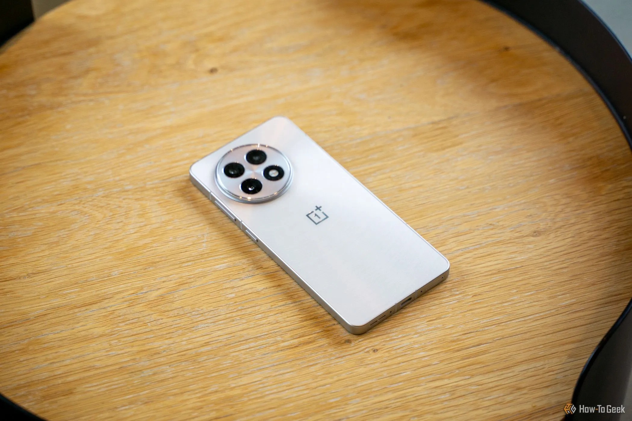 OnePlus 13R đặt úp màn hình trên bàn gỗ, để lộ cụm camera.