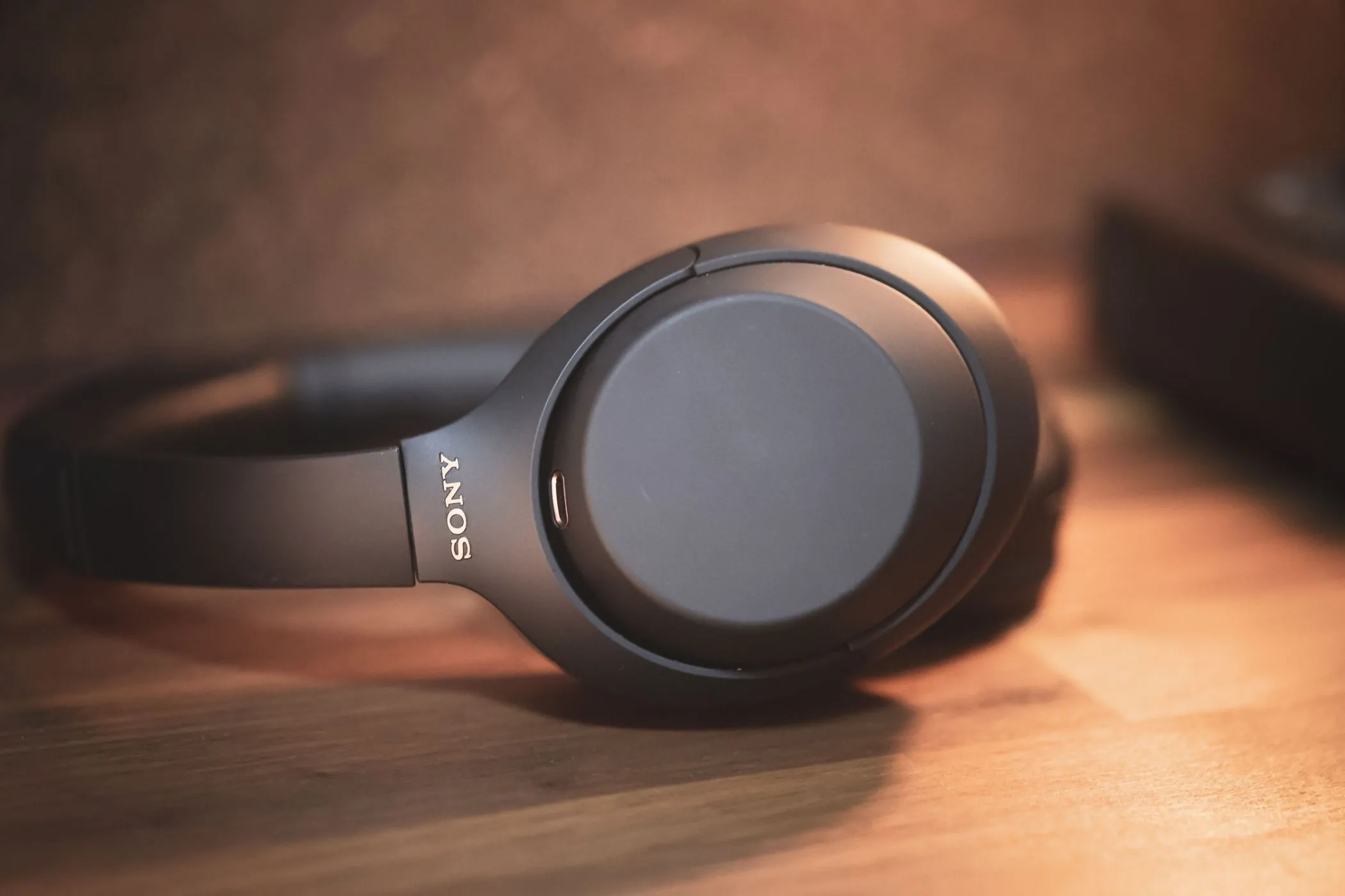 Tai nghe không dây chống ồn Sony WH-1000XM4 màu đen đặt trên bề mặt phẳng, nổi bật công nghệ khử tiếng ồn.
