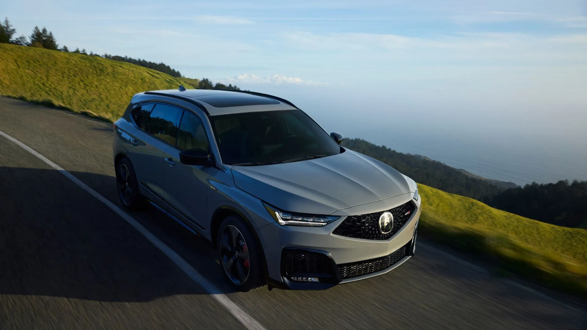 Acura MDX Type S Advance 2025 màu xám bạc đang lướt trên con đường nông thôn, tôn lên vẻ thể thao và năng động