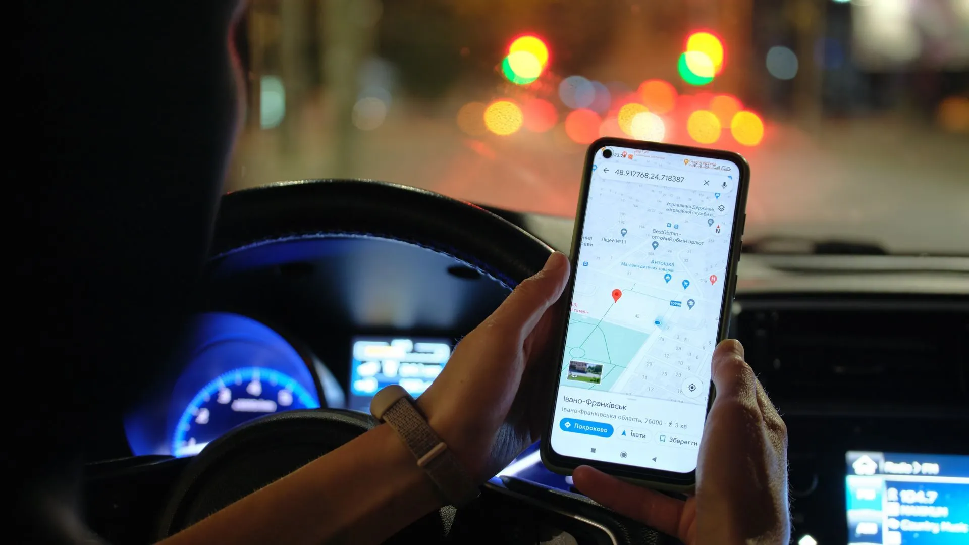 Ảnh cận cảnh tay tài xế đang cầm smartphone với ứng dụng Google Maps tìm kiếm địa điểm, thể hiện tính năng tìm kiếm tích hợp của ứng dụng dẫn đường.