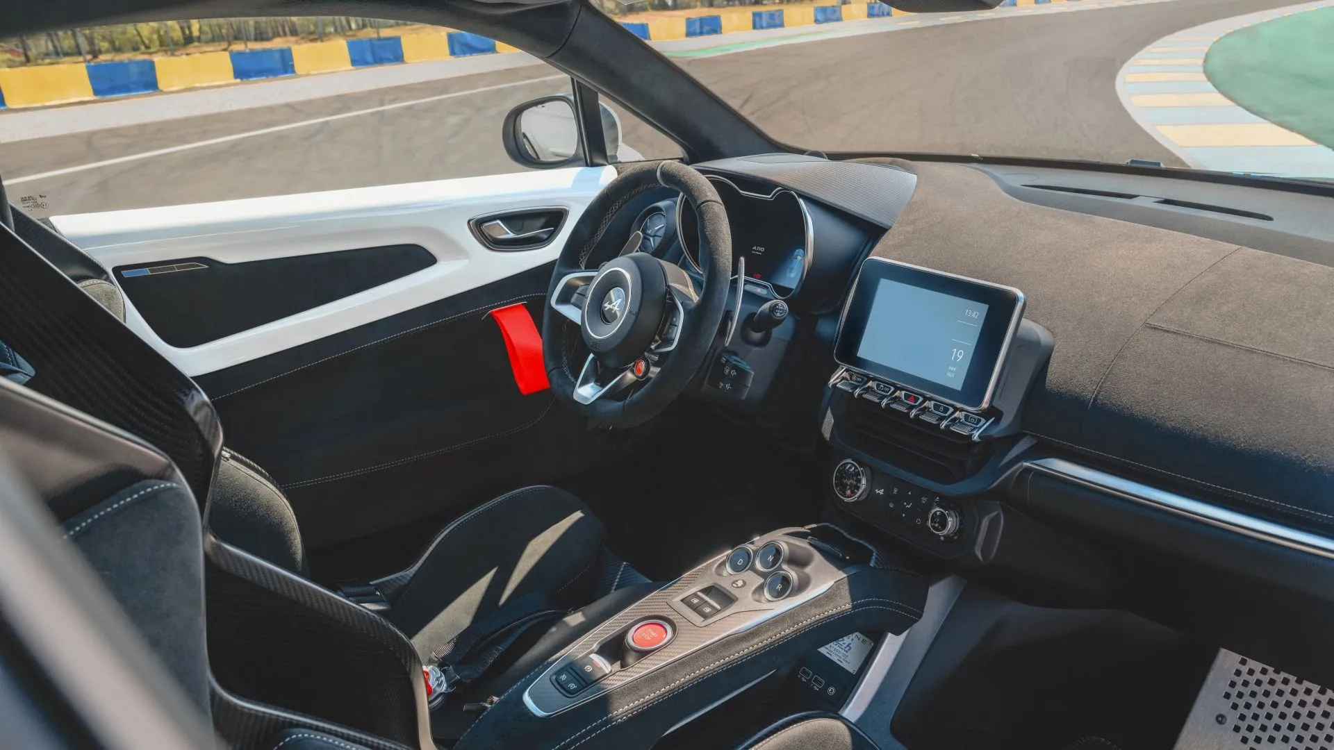 Ảnh nội thất xe Alpine A110 R 2025, tập trung vào bảng điều khiển trung tâm và màn hình thông tin giải trí, thể hiện sự kết hợp giữa thiết kế tối giản và công nghệ hiện đại trong buồng lái.