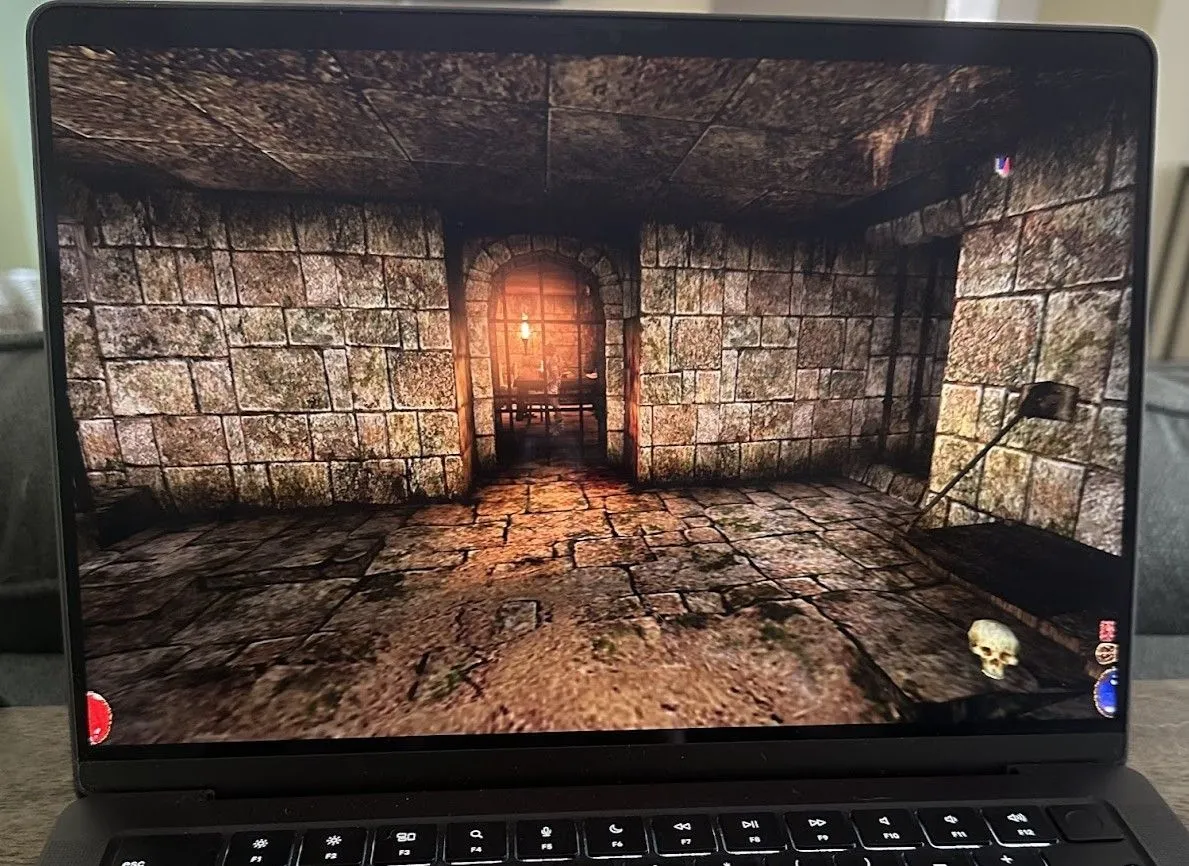 Arx Fatalis đang chạy trên MacBook Pro, hiển thị giao diện game nhập vai giả tưởng với nhân vật chính và môi trường hầm ngục đá cổ kính.