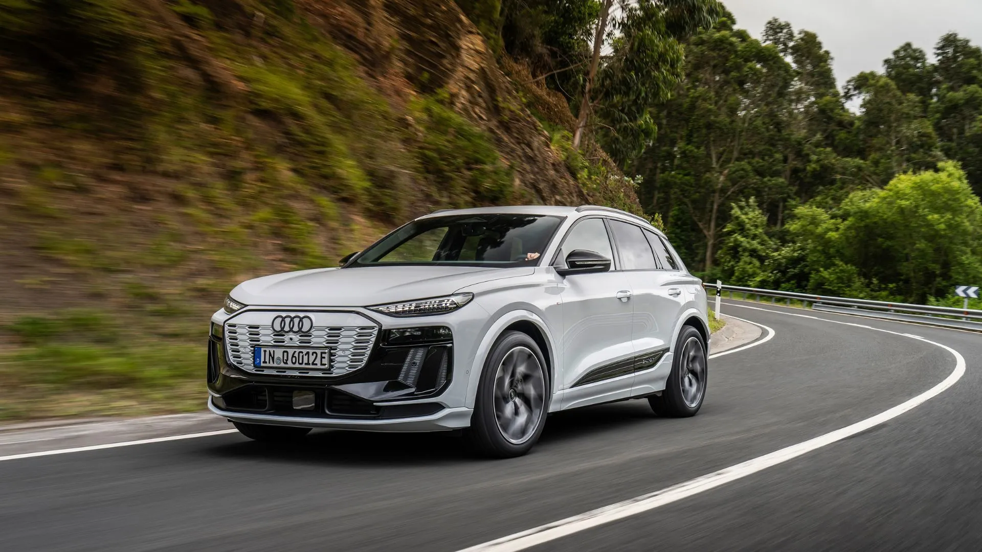 Audi Q6 e-tron màu trắng chạy trên cung đường đèo uốn lượn, nổi bật khả năng vận hành xe điện