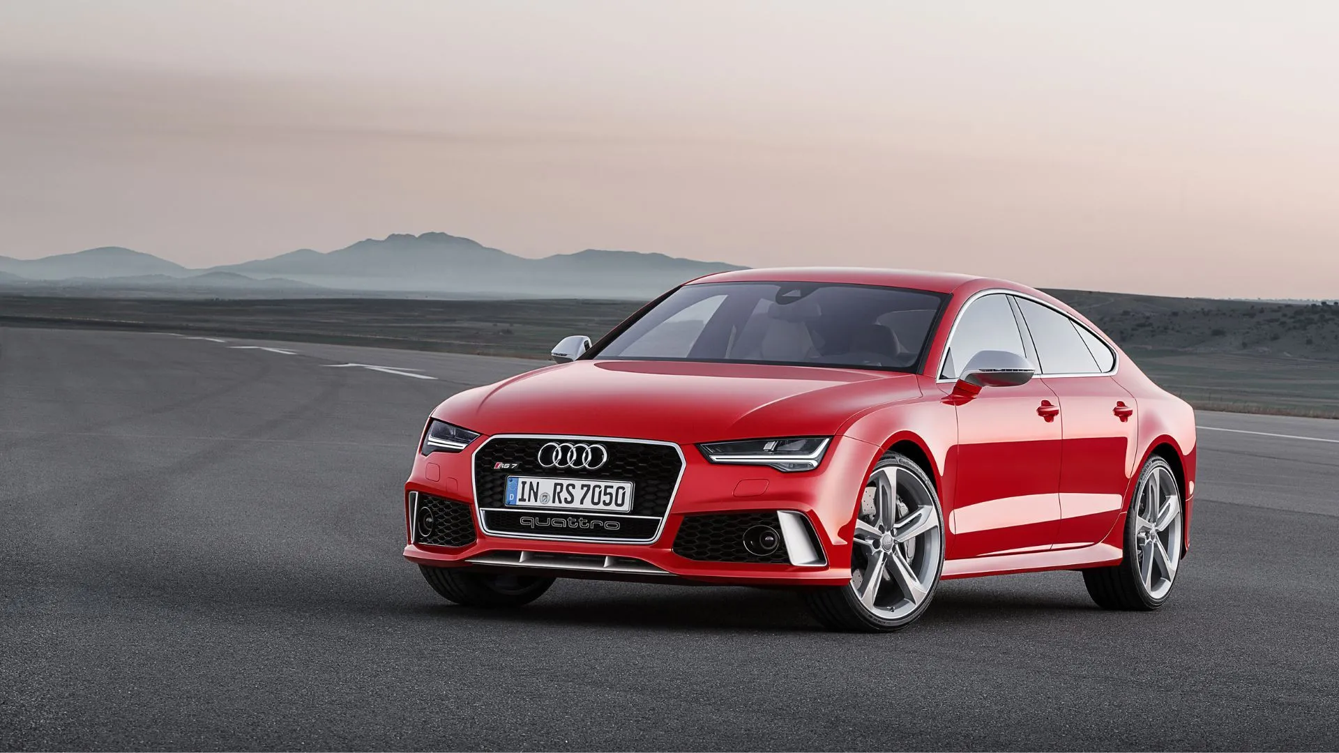 Audi RS7 2015 màu đỏ đậu trên đường nhựa với núi non phía sau