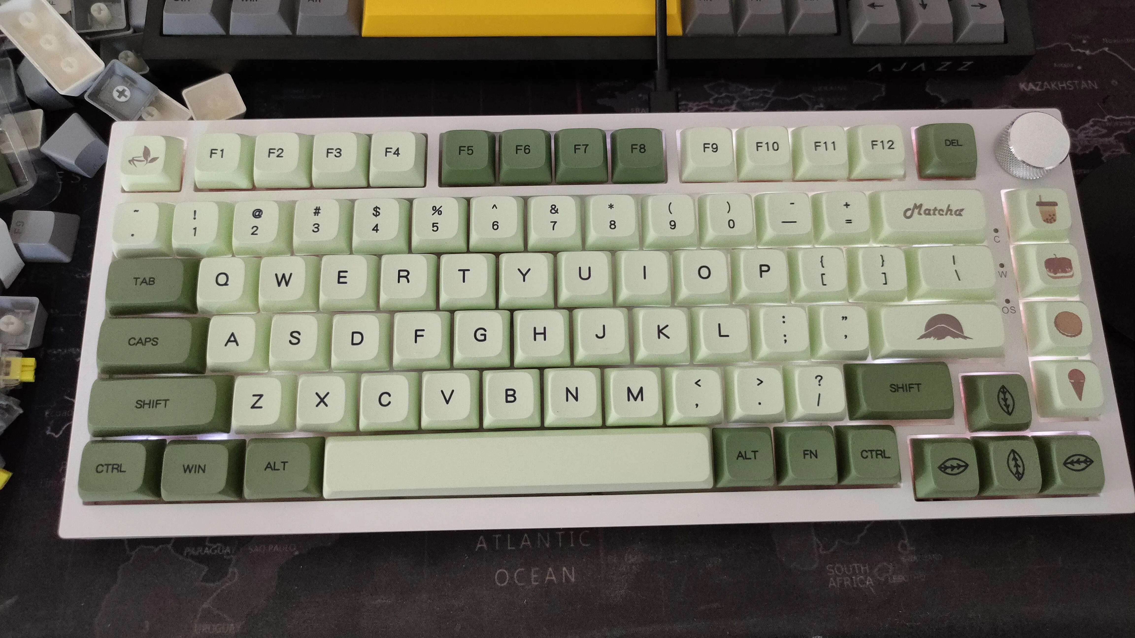 Bàn phím cơ Ajazz AK820 với keycap xanh tùy chỉnh trên thảm lót bàn, giúp giảm tiếng ồn và tăng sự ổn định.
