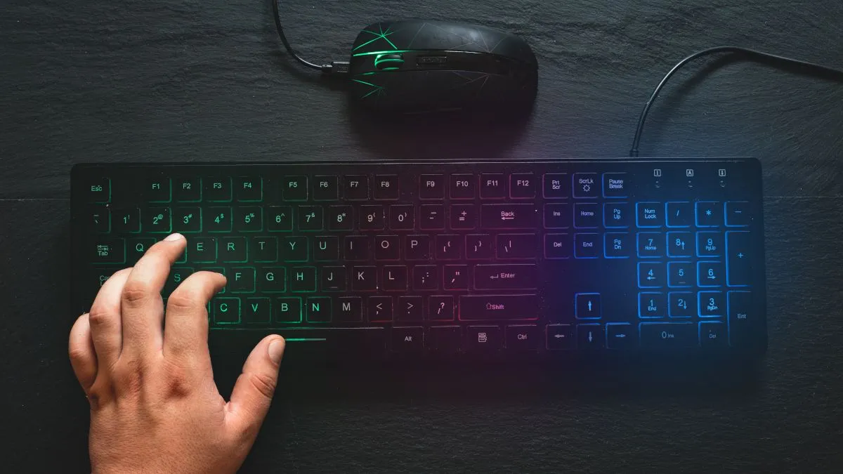 Bàn phím và chuột chơi game có đèn RGB, với bàn tay đặt trên bàn phím