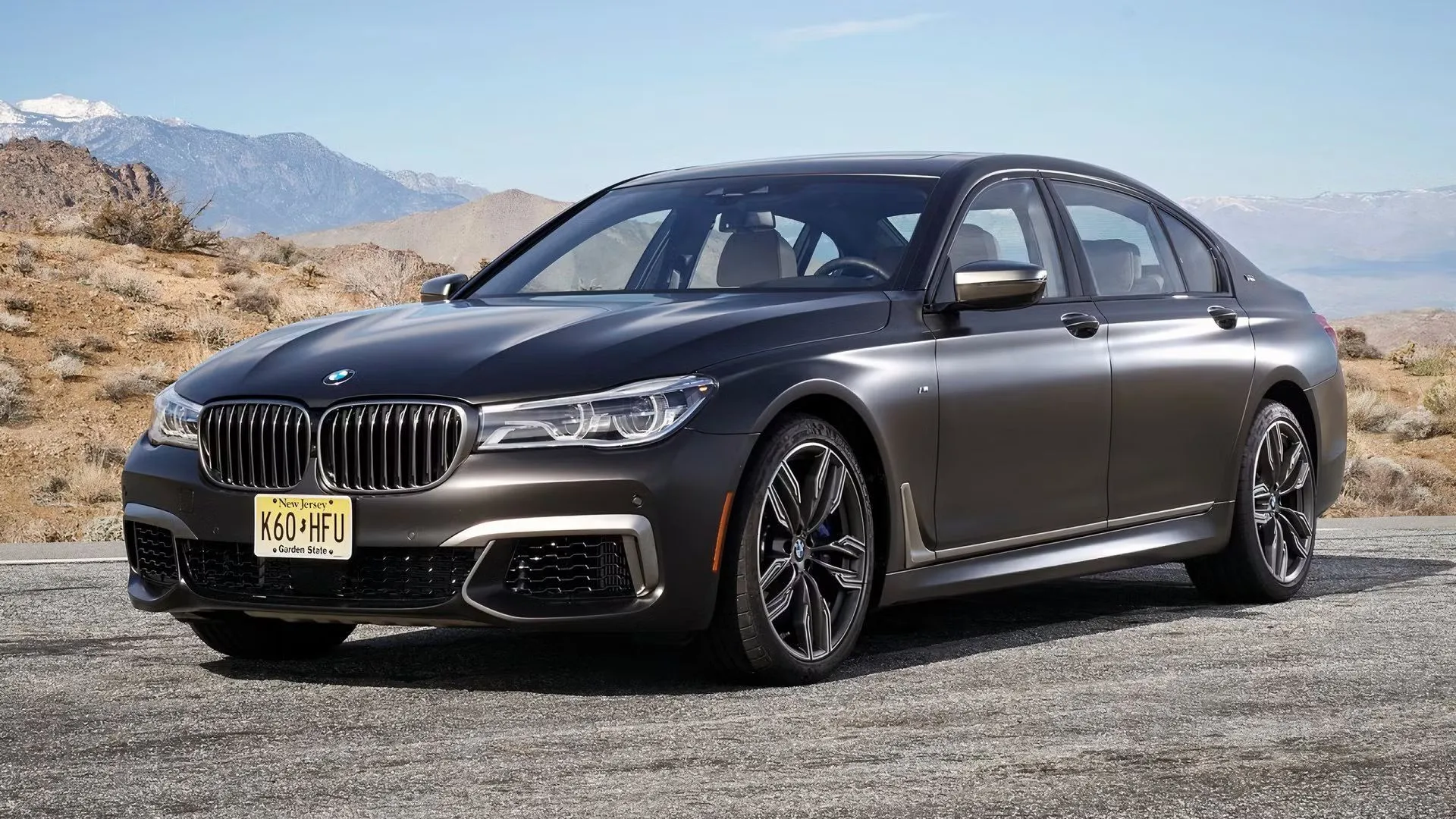 BMW M760i xDrive 2018 màu xám bạc đậu trên nền sa mạc, biểu tượng của sự sang trọng và mạnh mẽ