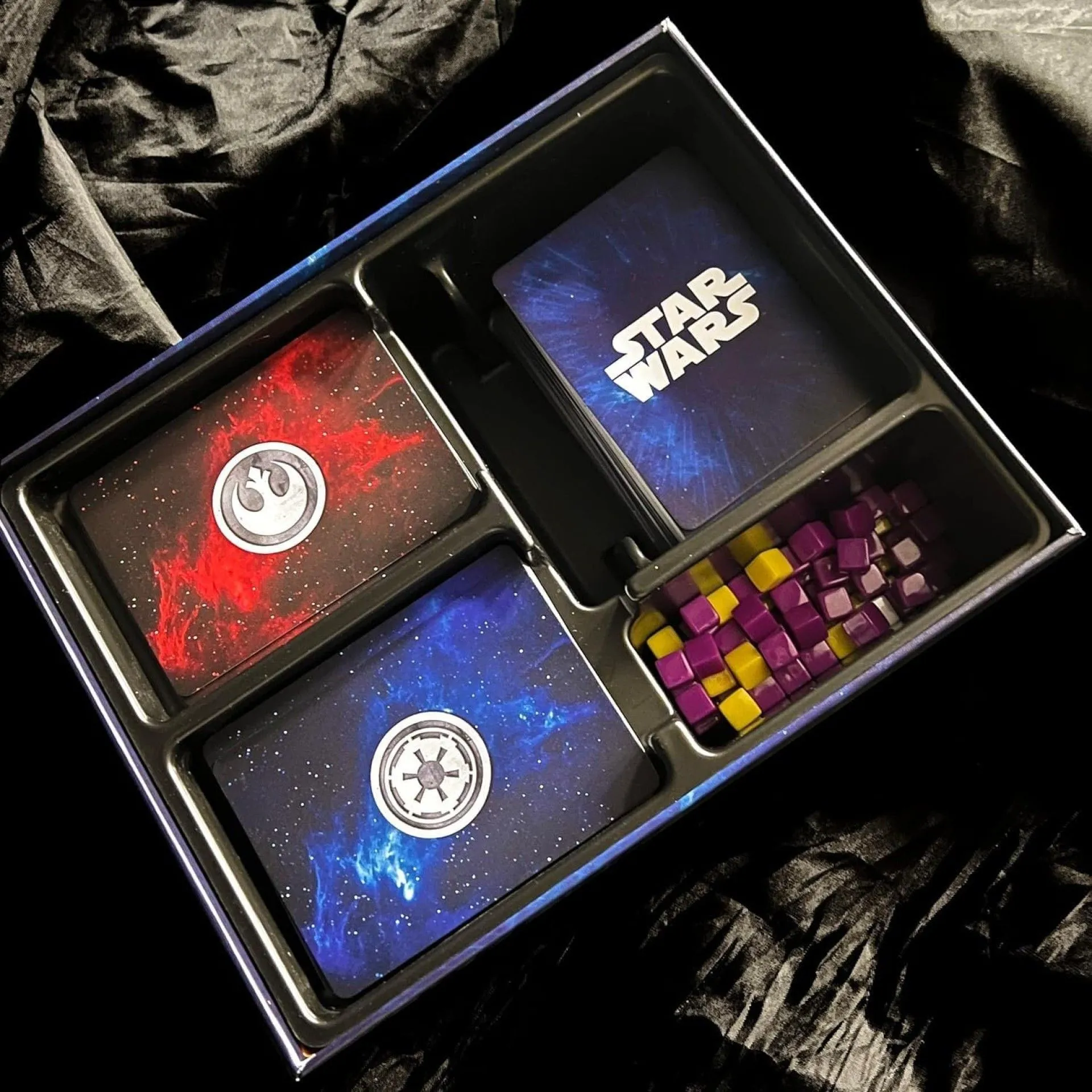 Các thành phần trong hộp game Star Wars: The DeckBuilding Game bao gồm thẻ bài, đồng xu và bàn chơi.