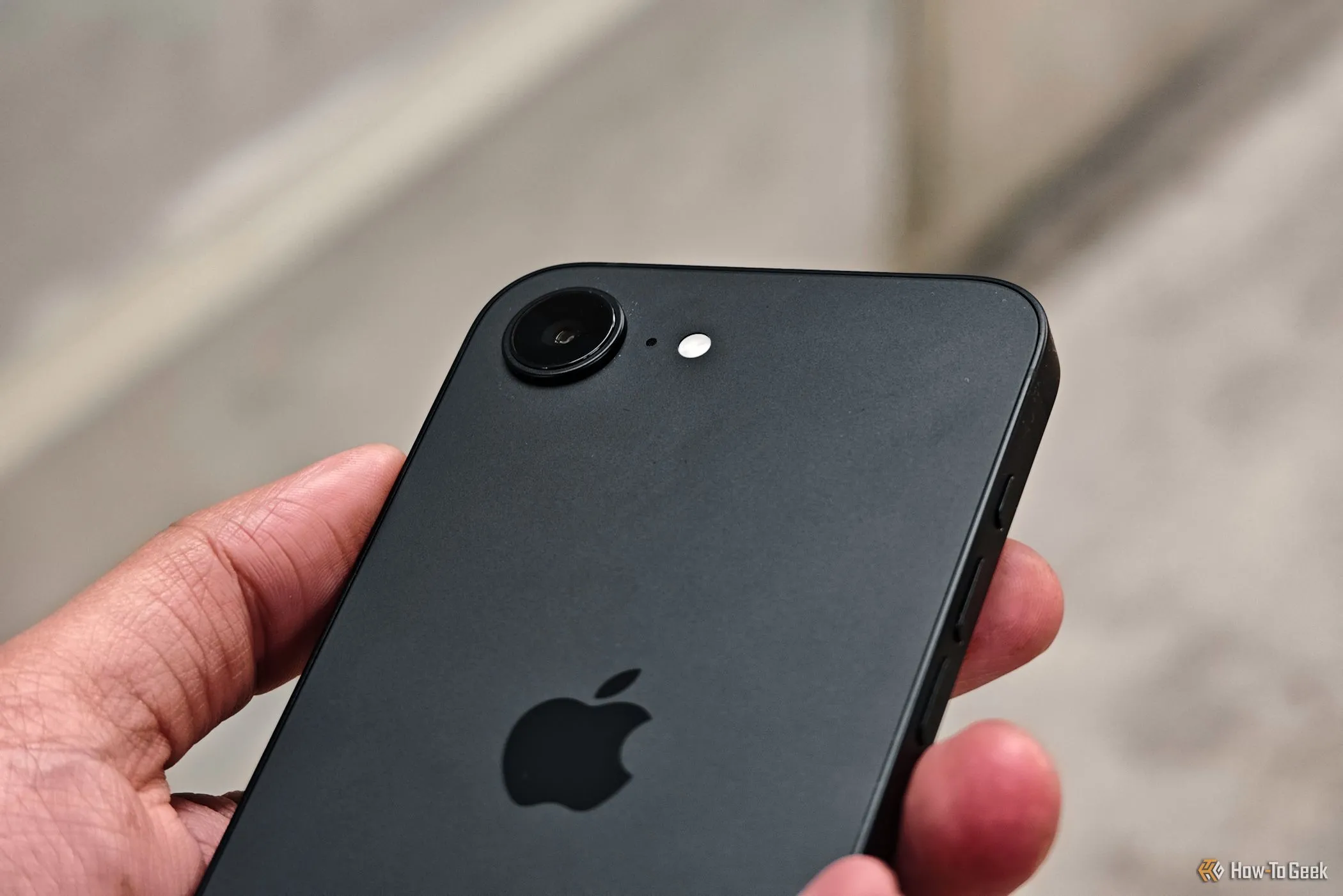 Cận cảnh cụm camera của iPhone 16e trong tay người dùng, thể hiện thiết kế và vị trí ống kính.
