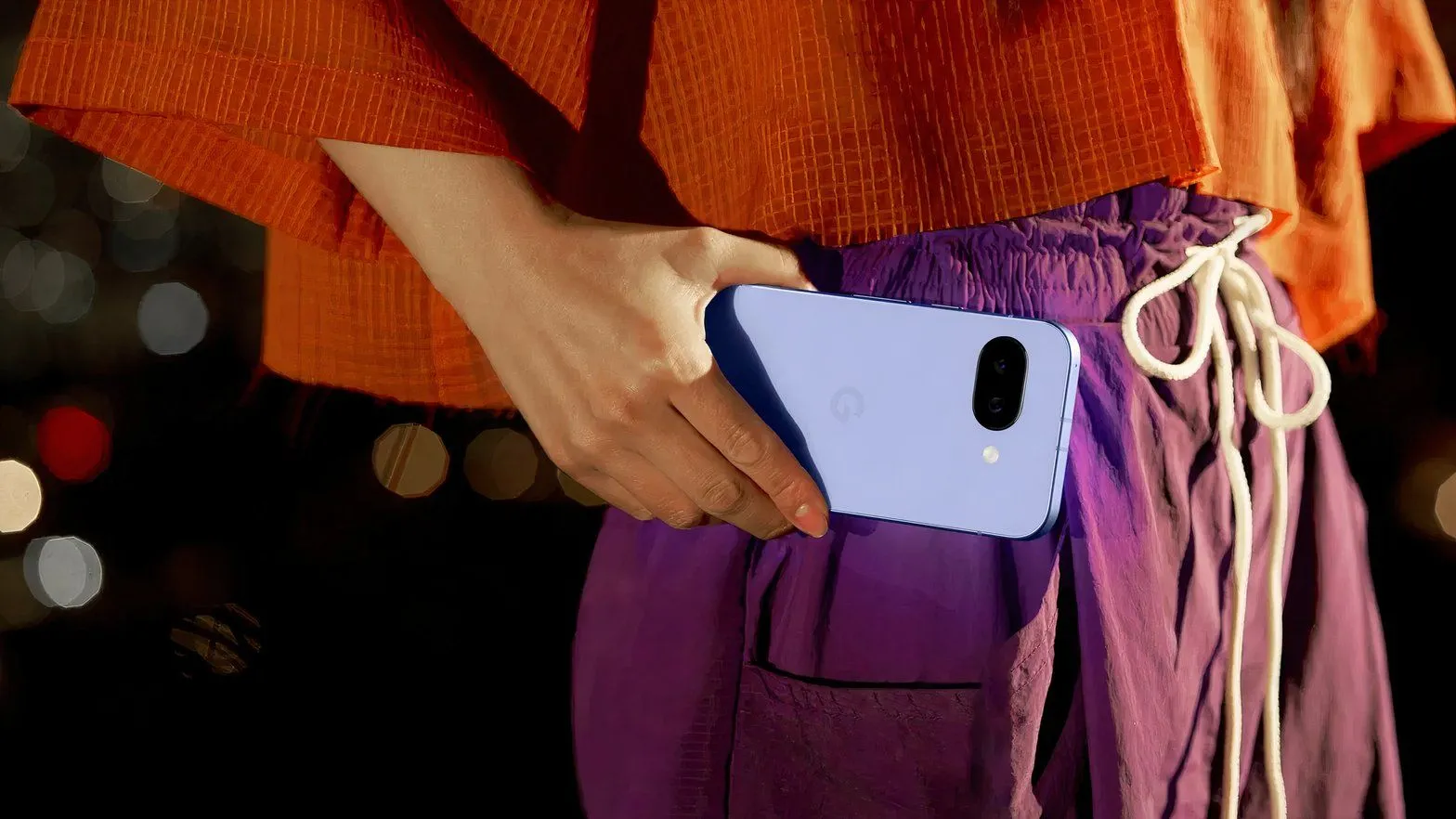 Cận cảnh một phụ nữ cầm điện thoại Google Pixel 9a, sẵn sàng chụp ảnh với camera đa năng. 