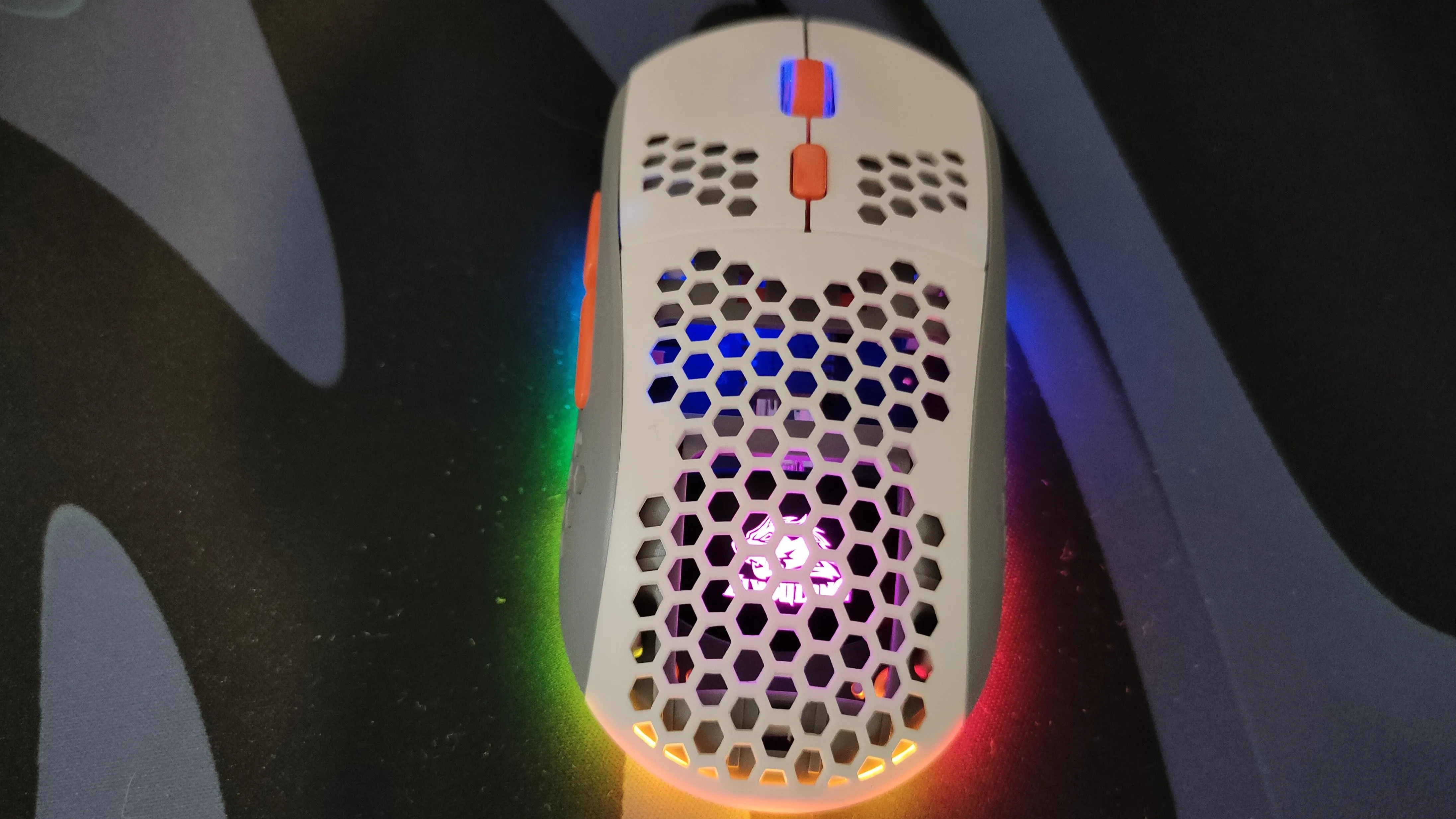 Chuột gaming siêu nhẹ màu trắng với thiết kế vỏ đục lỗ và đèn RGB.