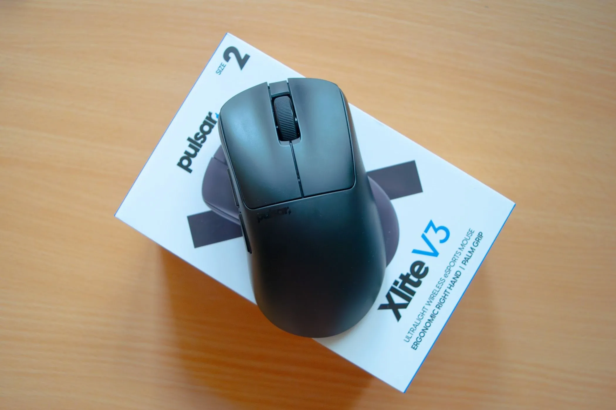Chuột gaming siêu nhẹ Pulsar Xlite V3 màu đen nằm trên vỏ hộp, làm nổi bật thiết kế ergonomic cho game thủ tay phải.