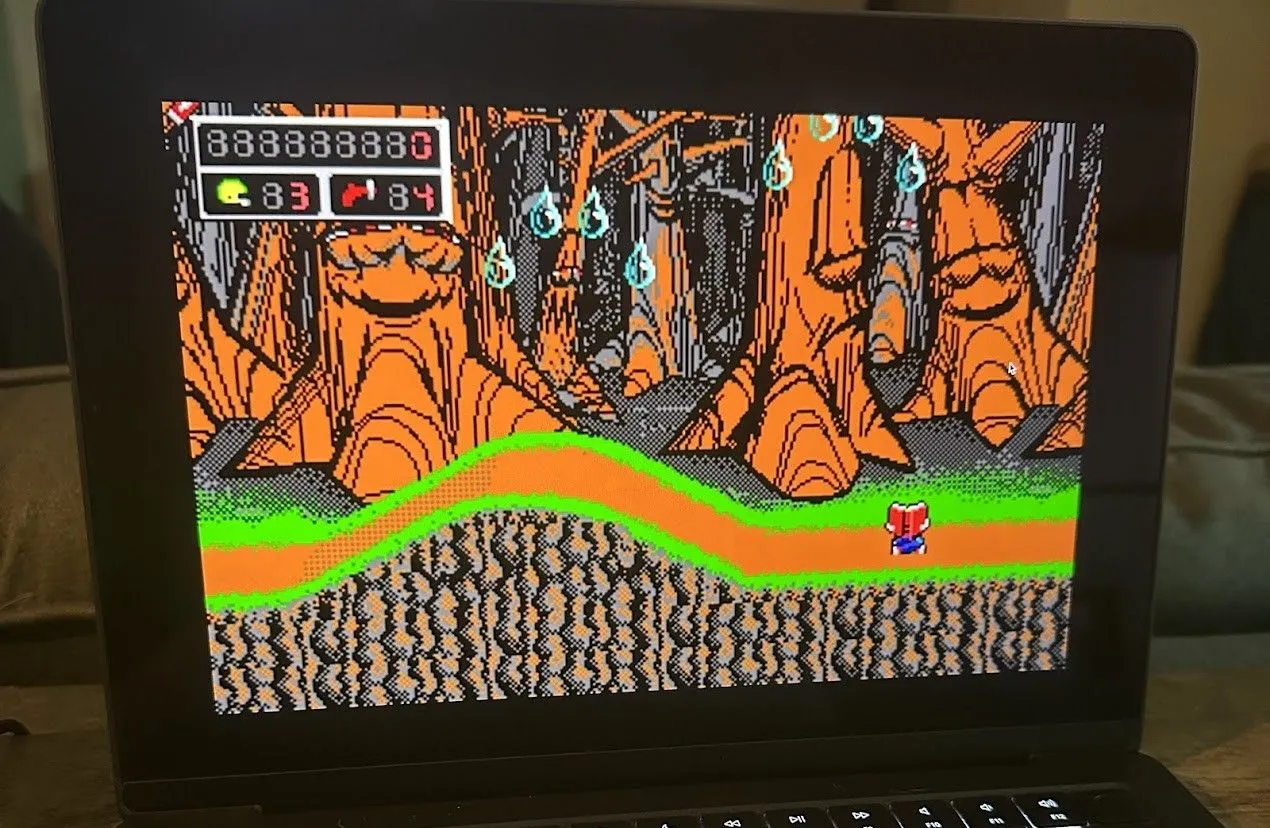 Commander Keen đang chạy trên MacBook Pro, hiển thị màn hình game platformer với nhân vật chính mặc bộ đồ không gian màu xanh và kẻ thù ngoài hành tinh.