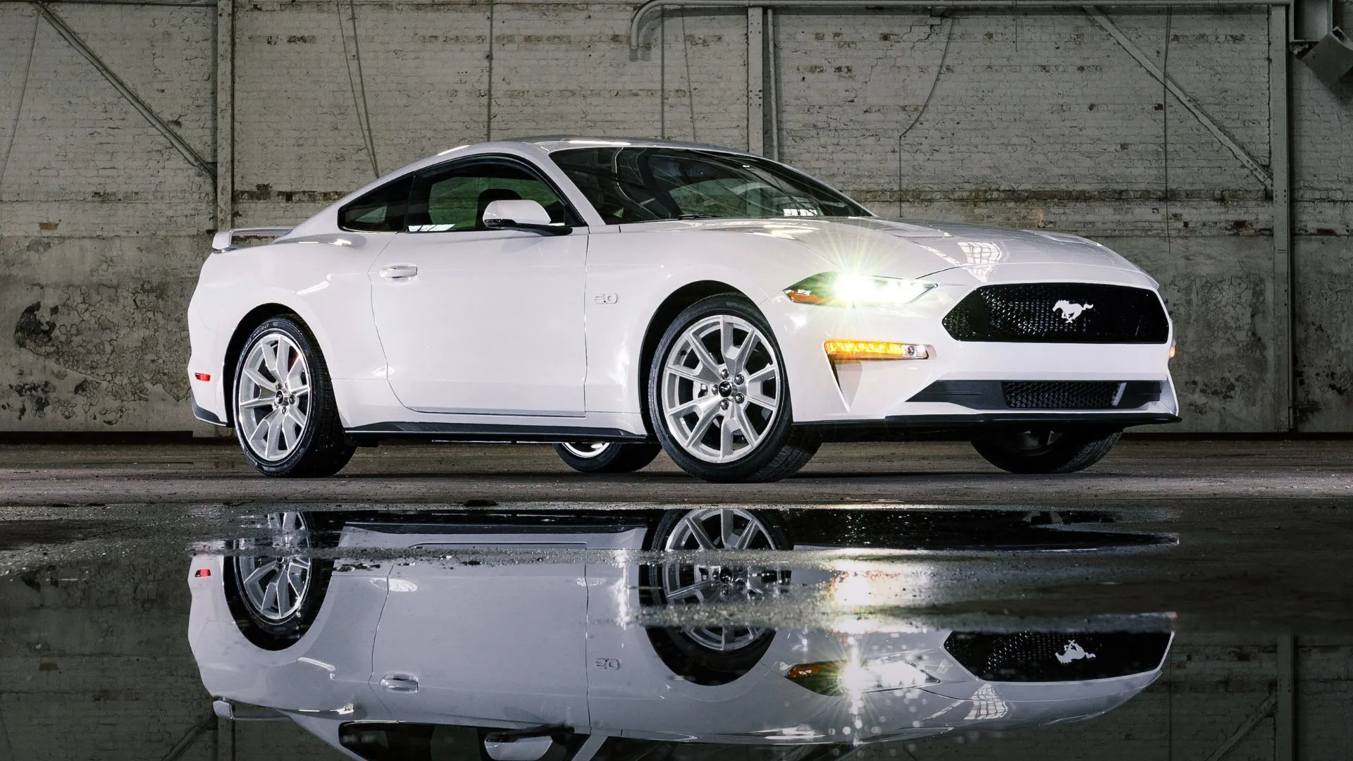 Ford Mustang Coupe 2022 màu trắng tinh tế đậu trong nhà kho với sàn ướt, toát lên vẻ mạnh mẽ và hiện đại của dòng xe Ford.