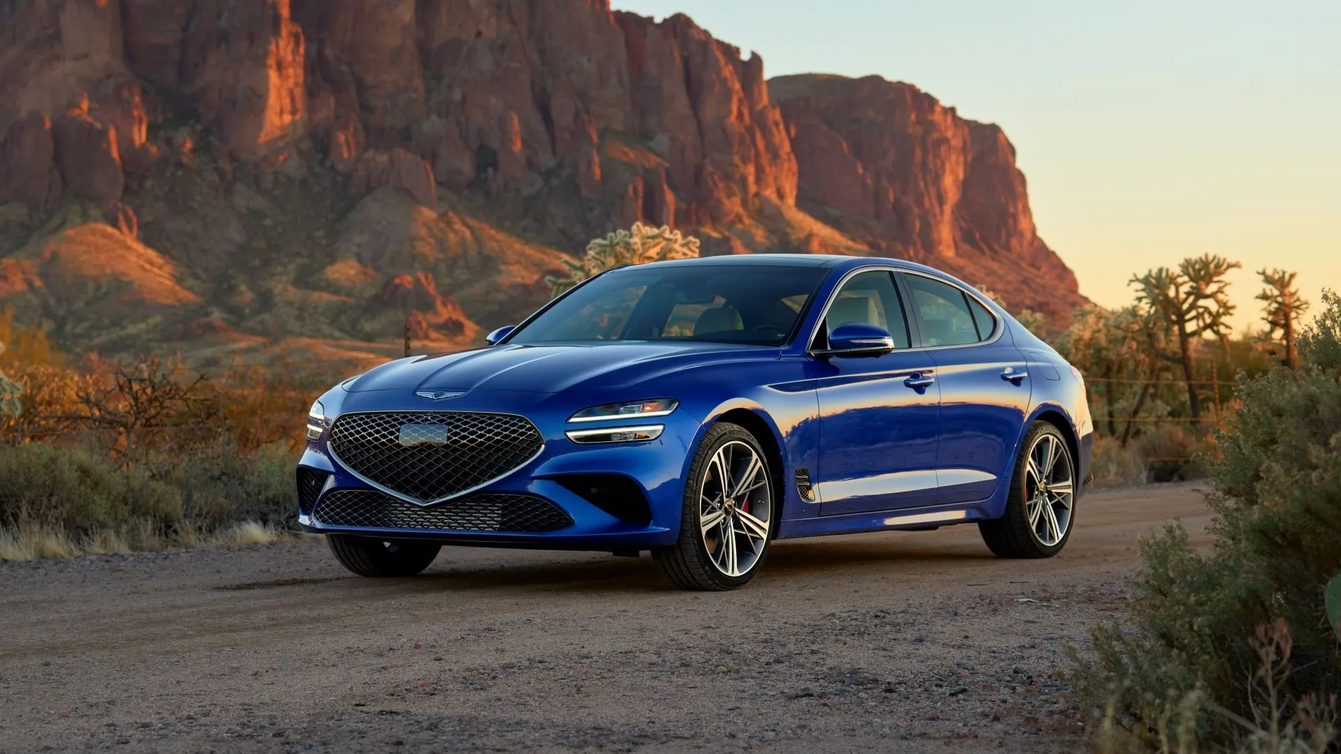 Genesis G70 2025 màu xanh dương đỗ xe, với góc nhìn 3/4 phía trước, thể hiện thiết kế sang trọng và thể thao của mẫu sedan hạng sang cỡ nhỏ.
