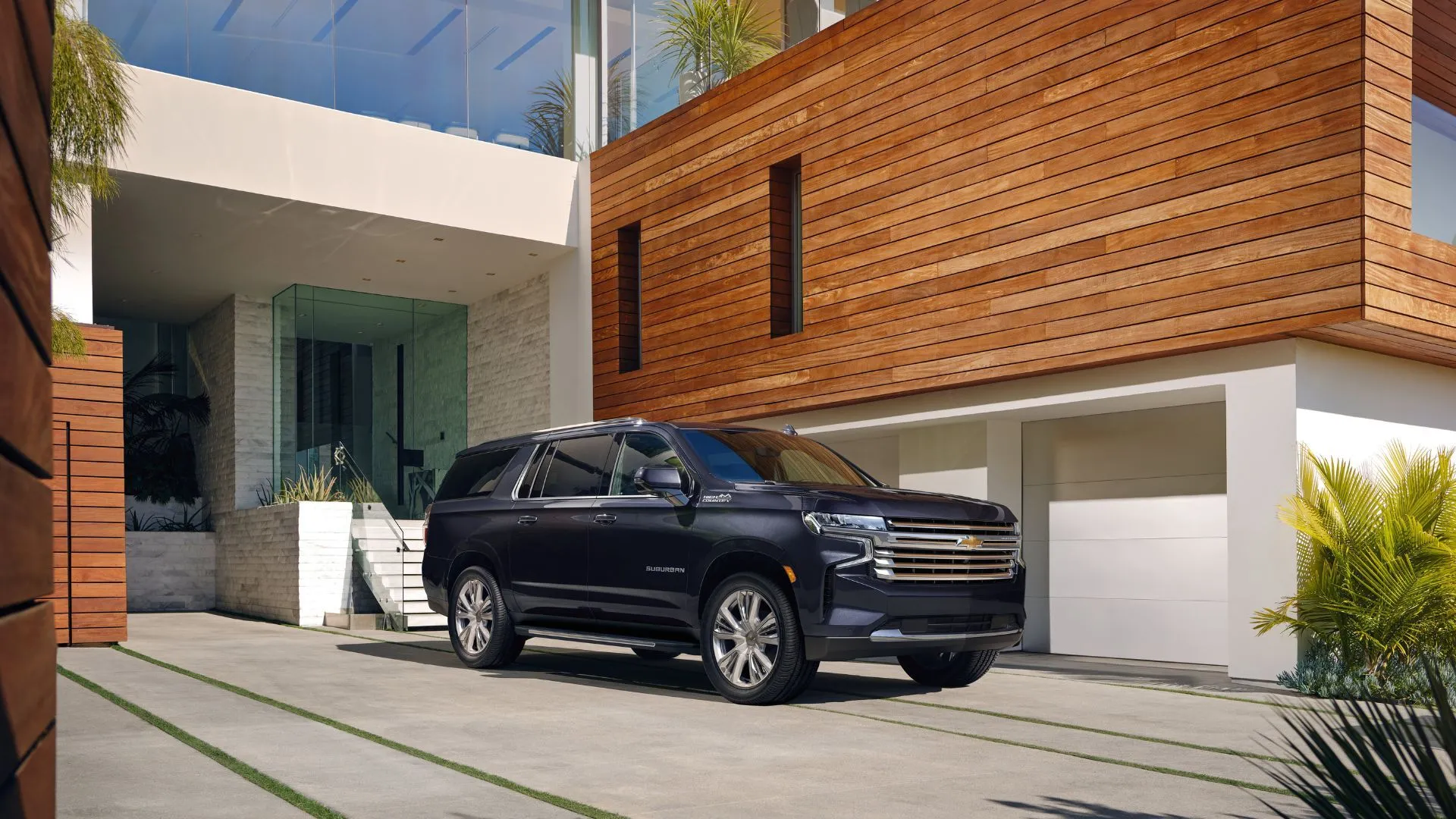 Góc ba phần tư phía trước của chiếc Chevrolet Suburban 2023 đậu bên ngoài một ngôi nhà.
