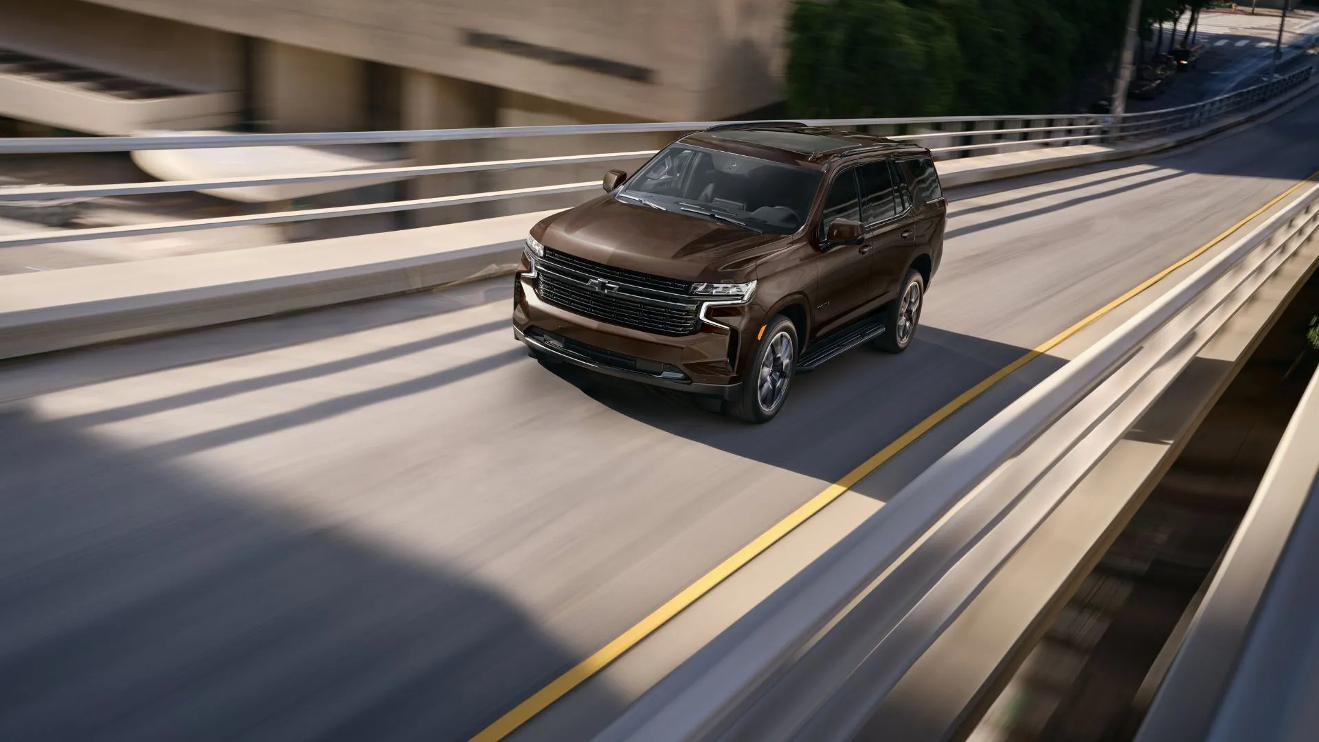 Góc ba phần tư phía trước của chiếc Chevrolet Tahoe 2023 màu nâu đang chạy trên đường cao tốc.