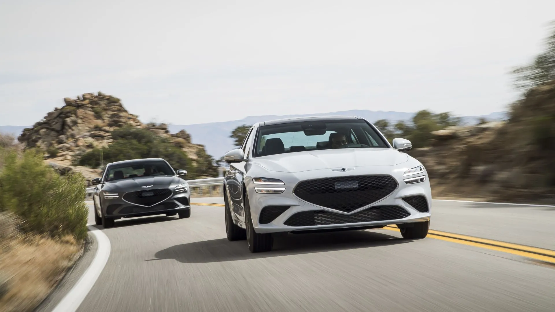 Hai chiếc Genesis G70 2025 màu tối và màu sáng đậu cạnh nhau, làm nổi bật thiết kế ngoại thất thể thao và lưới tản nhiệt đặc trưng.