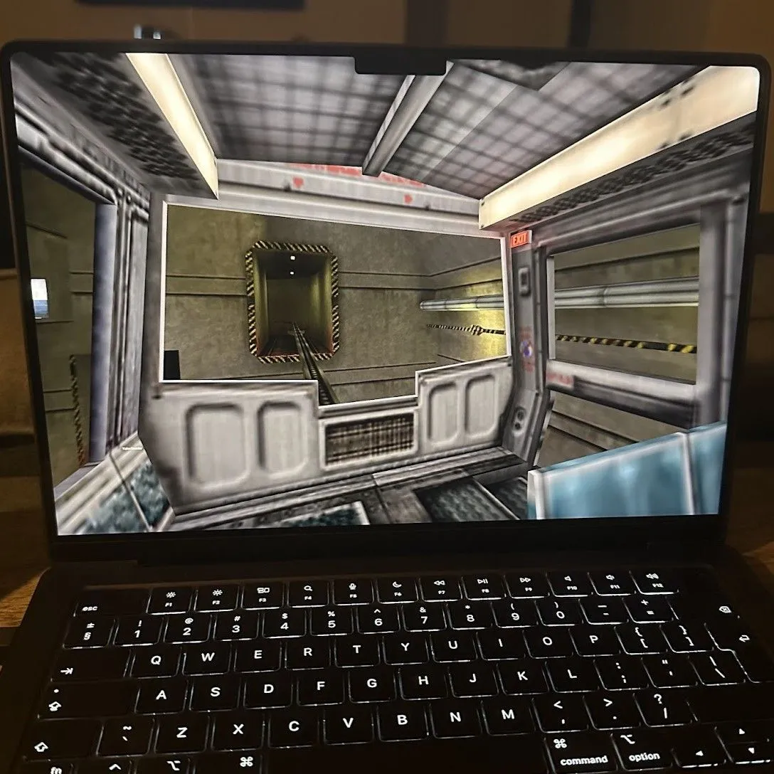 Half-Life đang chạy trên MacBook Pro, hiển thị nhân vật Gordon Freeman trong môi trường phòng thí nghiệm với máy móc và ánh sáng xanh.
