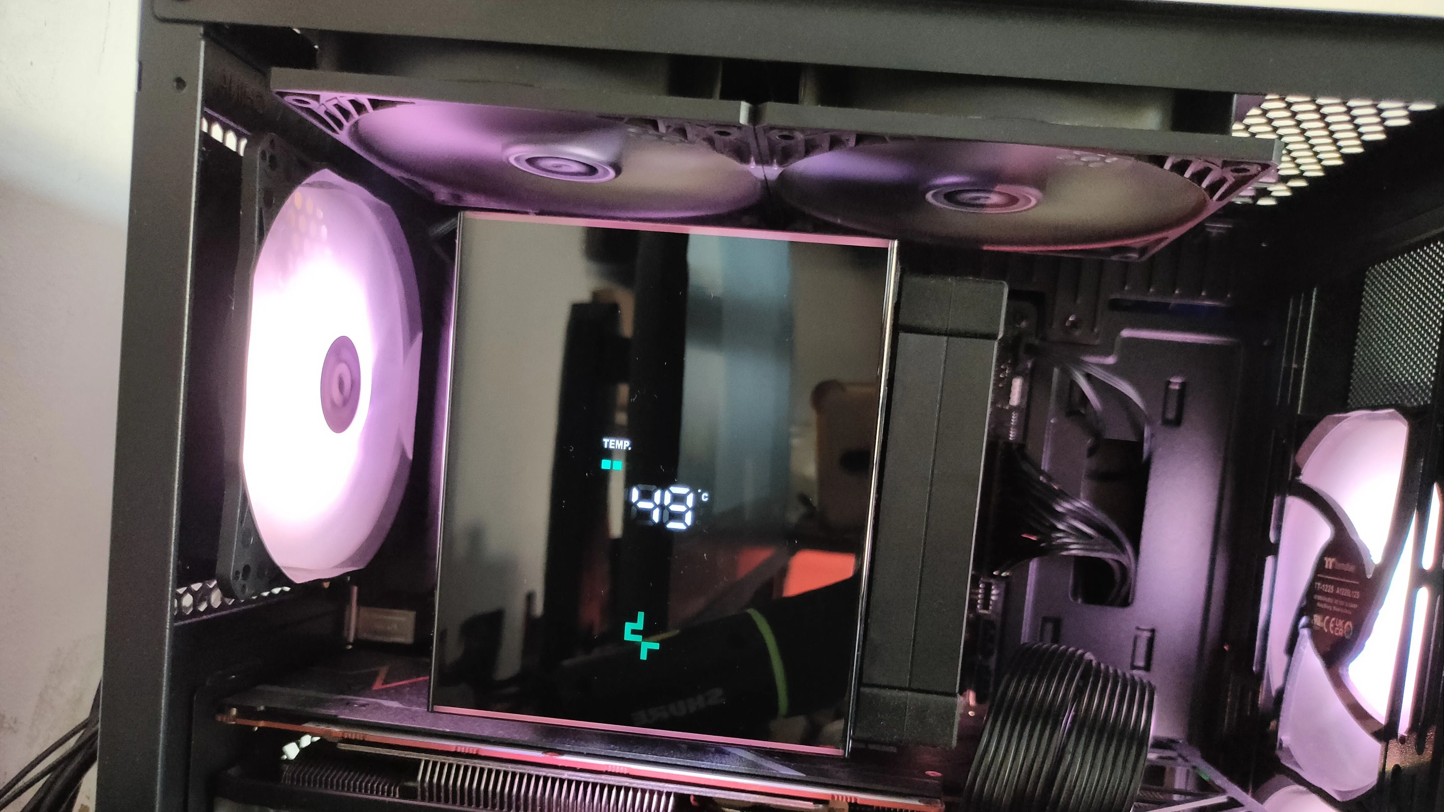 Hệ thống tản nhiệt khí CPU hiện đại với màn hình hiển thị, cùng các quạt tản nhiệt RGB ở phía trên và phía sau thùng máy, tôn lên vẻ đẹp của PC.