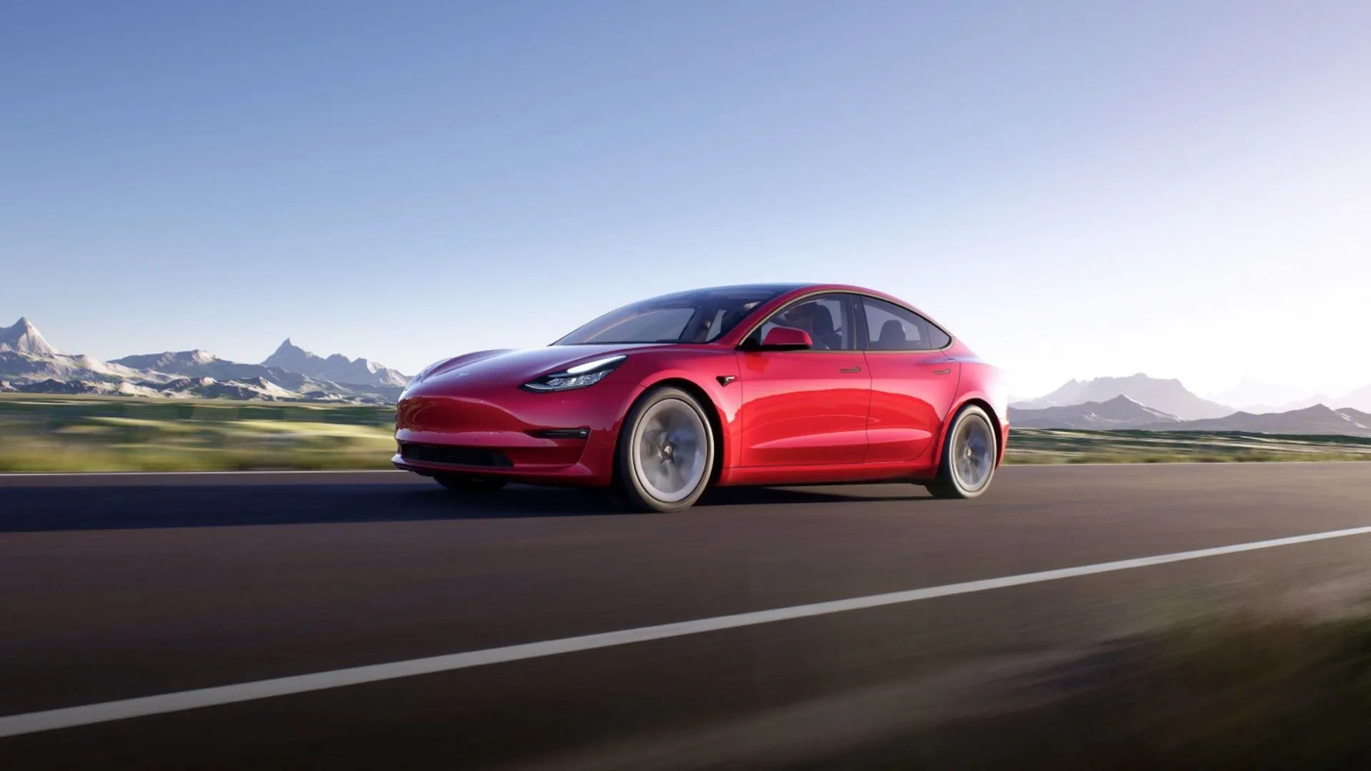 Hình ảnh chiếc Tesla Model 3 màu đỏ năng động chạy trên con đường nông thôn với núi phủ tuyết trắng, minh họa cho sức hấp dẫn của mẫu xe điện này ngay cả khi đã qua sử dụng.