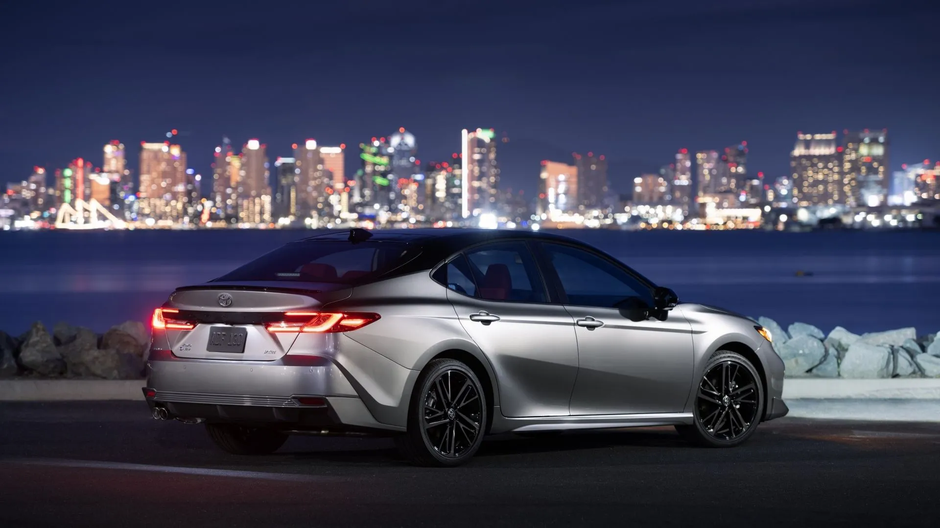 Hình ảnh góc 3/4 phía sau của Toyota Camry 2025 XSE AWD với thiết kế thể thao và nóc xe màu đen ấn tượng.