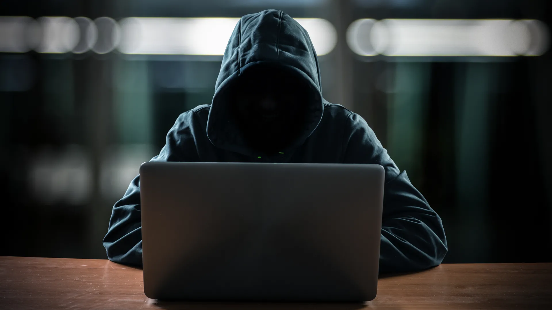 Hình ảnh hacker bí ẩn ngồi trước màn hình máy tính, tượng trưng cho các mối đe dọa bảo mật và rủi ro từ việc sạc công cộng như &quot;juice jacking&quot;.