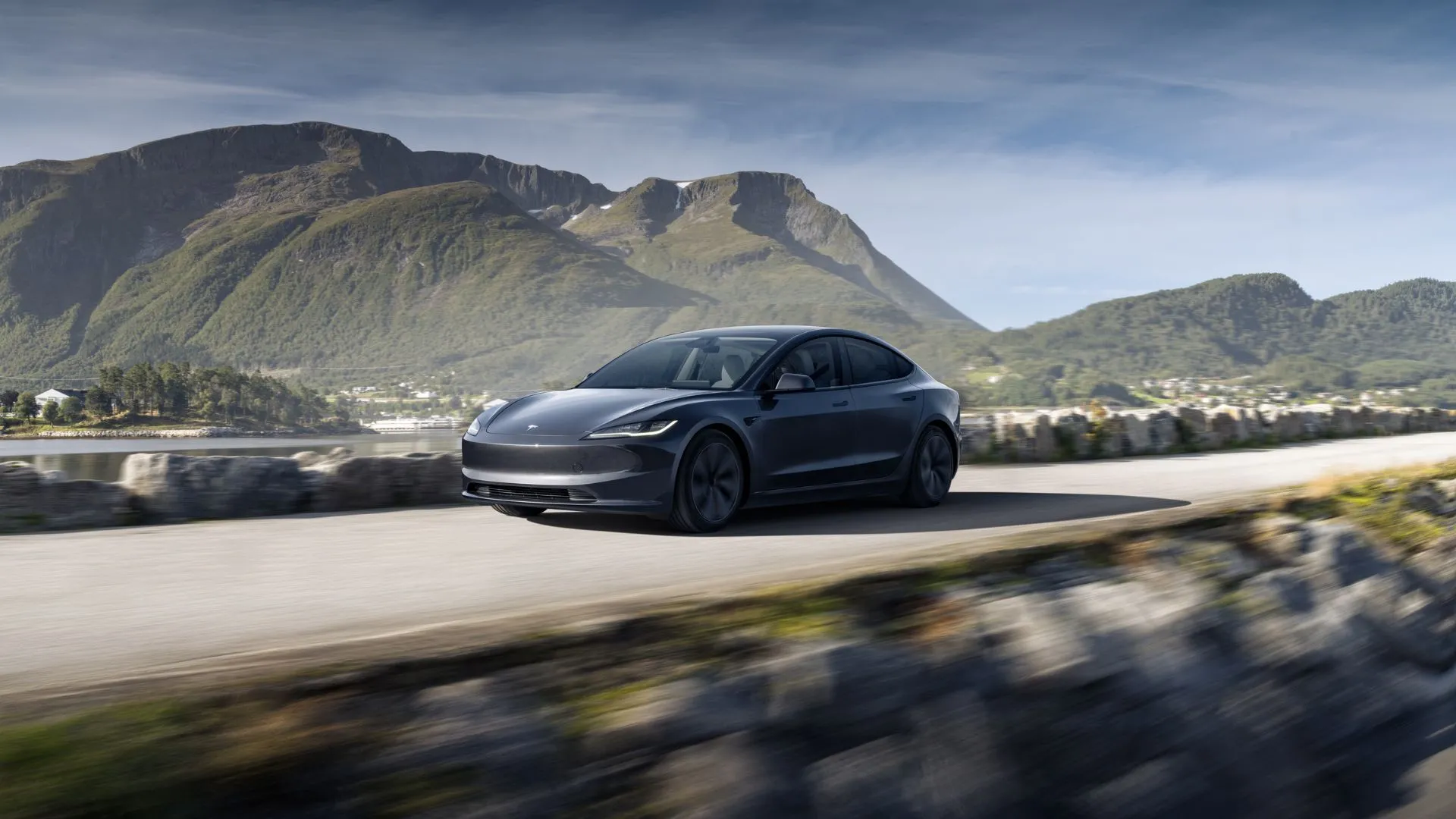 Hình ảnh sedan điện Tesla Model 3 2025 màu xám với khung cảnh núi non hùng vĩ phía sau, nhấn mạnh vẻ đẹp và hiệu suất.
