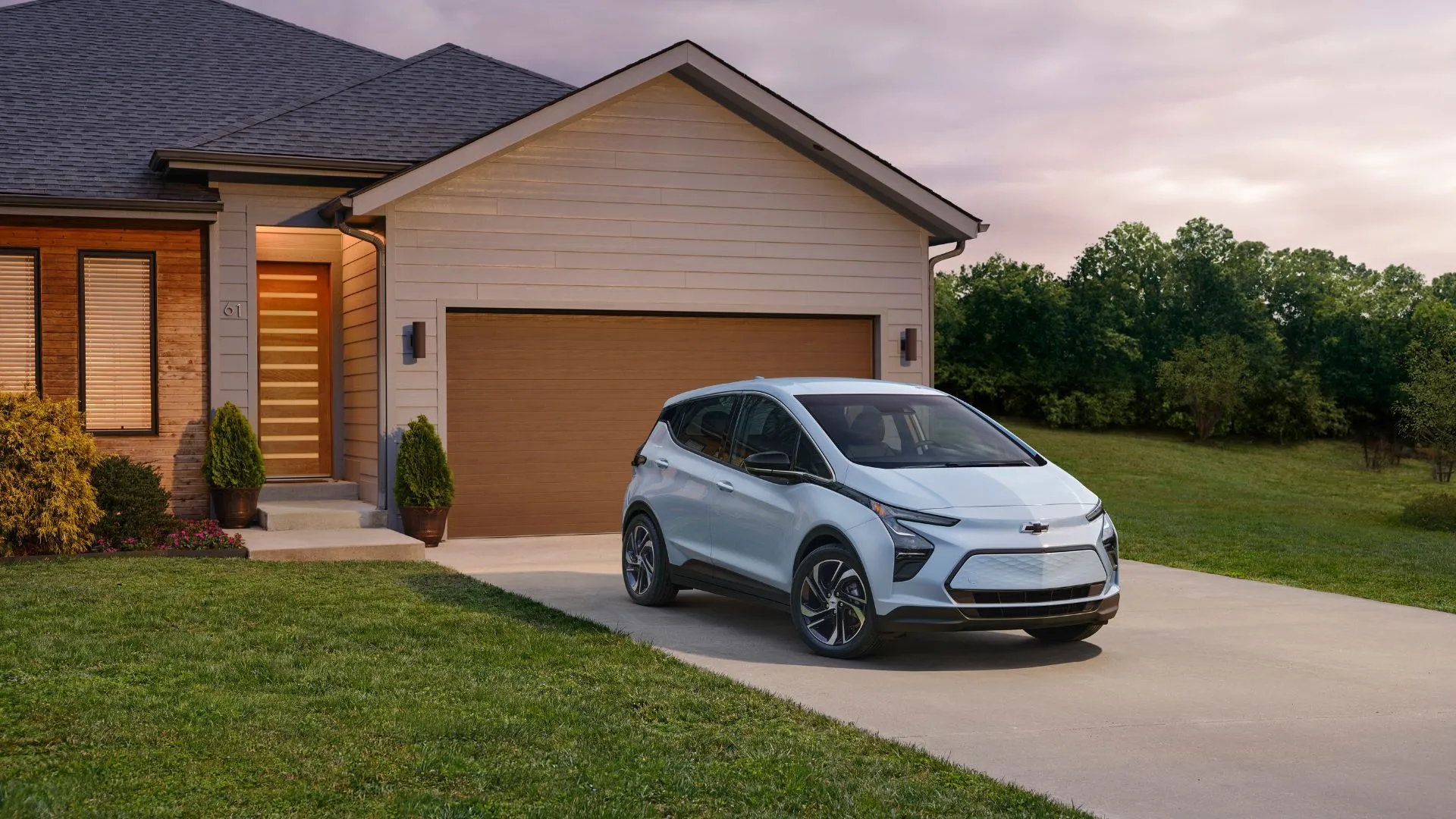 Hình ảnh tĩnh góc 3/4 phía trước của Chevrolet Bolt EV 2023 màu xanh dương đỗ trước nhà, thể hiện thiết kế xe điện thông minh và sẵn sàng sử dụng hàng ngày.