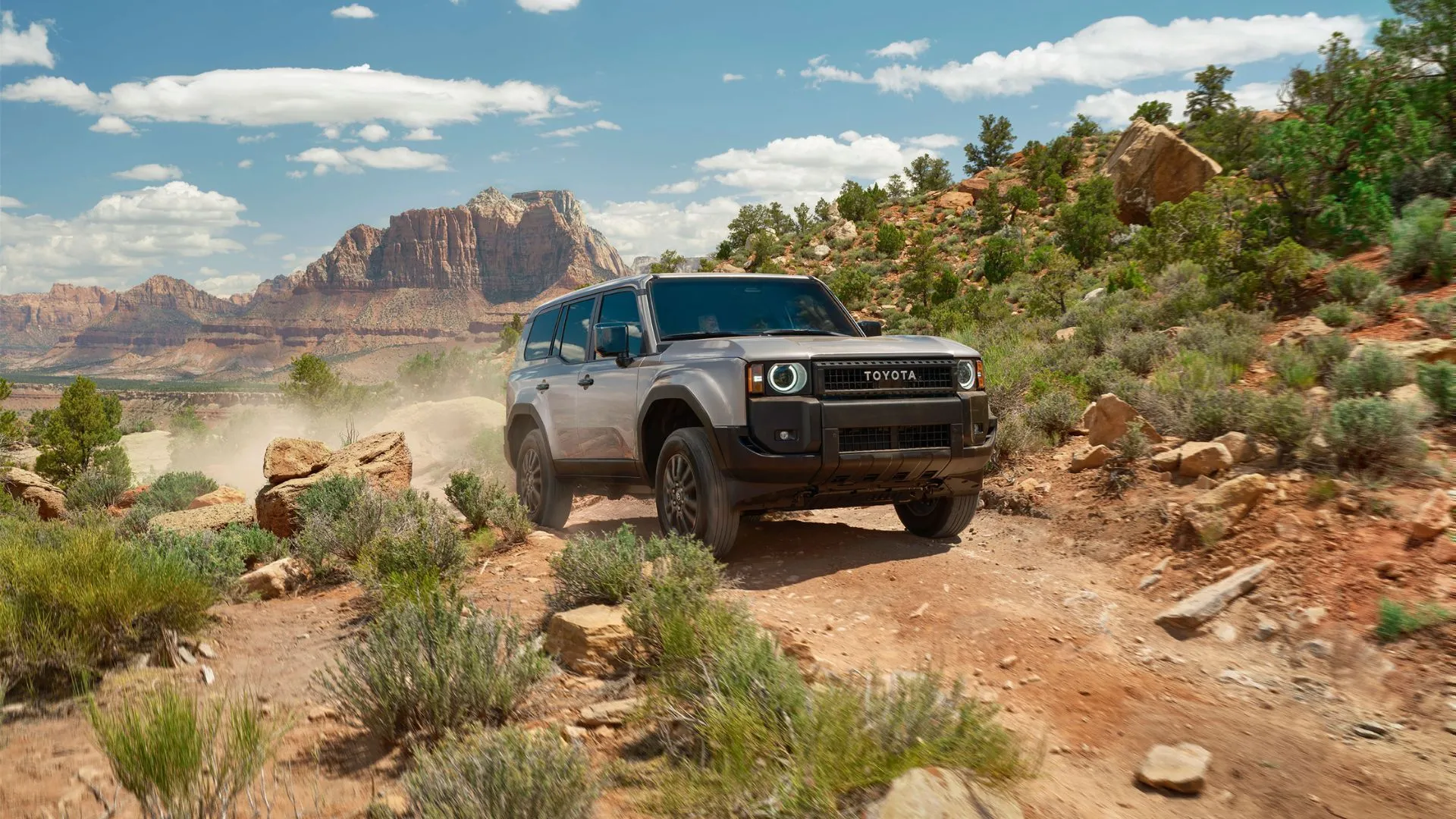 Hình ảnh Toyota Land Cruiser 2025 màu bạc chạy off-road trên địa hình sa mạc gồ ghề, thể hiện khả năng vượt mọi địa hình mạnh mẽ của dòng xe huyền thoại này.