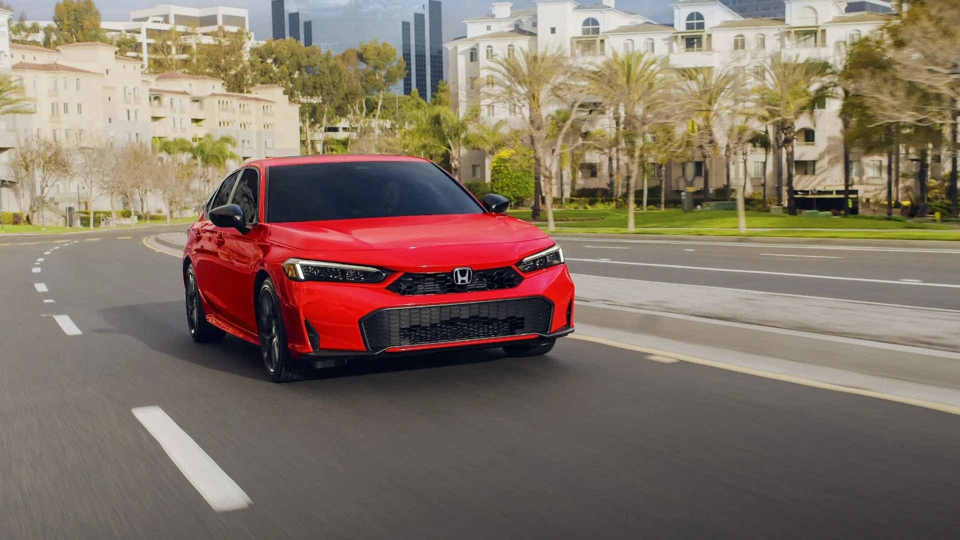 Honda Civic Sedan Sport Hybrid 2025 màu đỏ mạnh mẽ lướt đi trên đường phố đô thị.