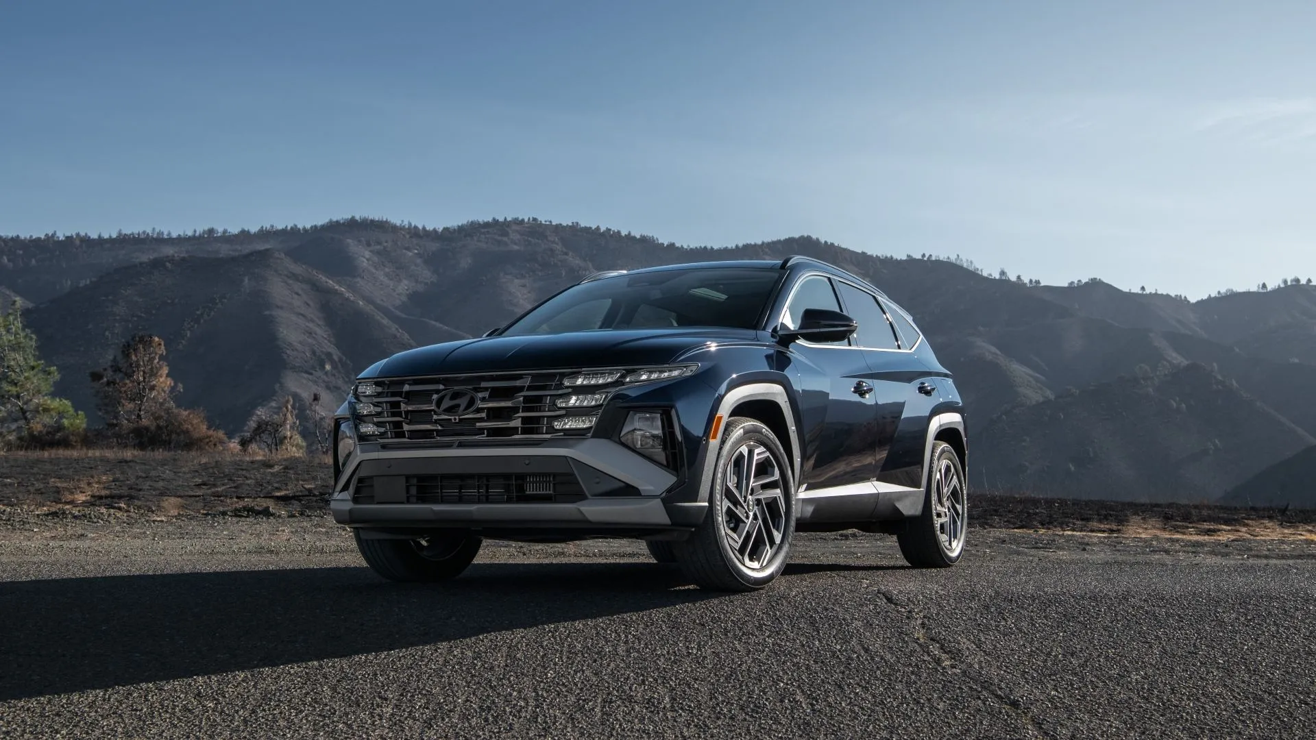 Hyundai Tucson Hybrid 2025 màu trắng, góc 3/4 phía trước, với thiết kế lưới tản nhiệt mới và hệ thống hybrid mạnh mẽ.