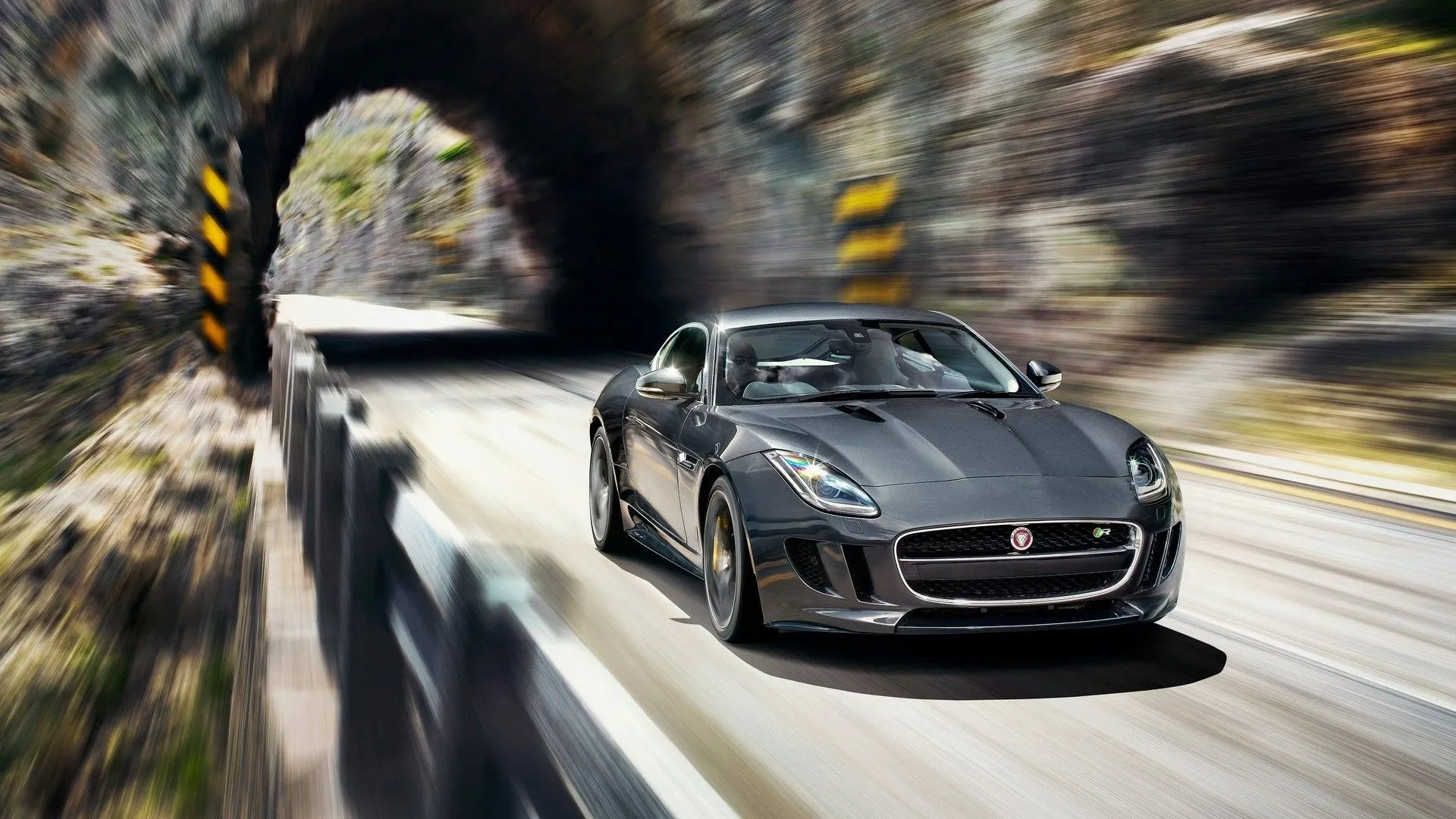 Jaguar F-Type V8 S 2014 màu xanh đậm đang phóng ra khỏi đường hầm với tốc độ cao