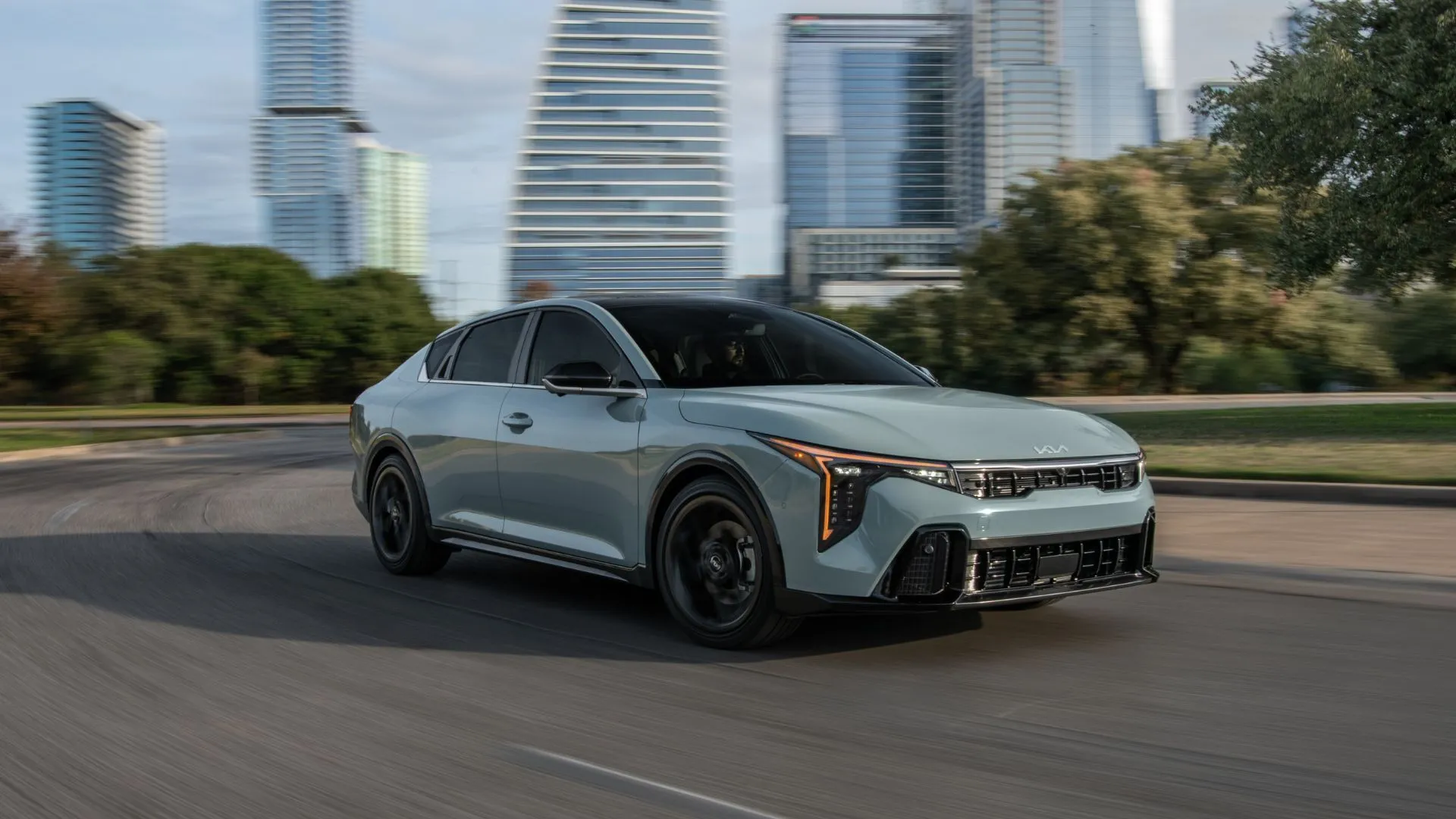 Kia K4 2025 màu xám hiện đại di chuyển trong khu vực đô thị.