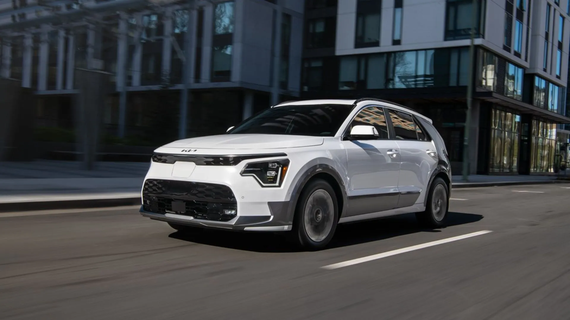 Kia Niro EV 2025 màu trắng đang di chuyển trên đường phố đông đúc, nổi bật với kiểu dáng nhỏ gọn.