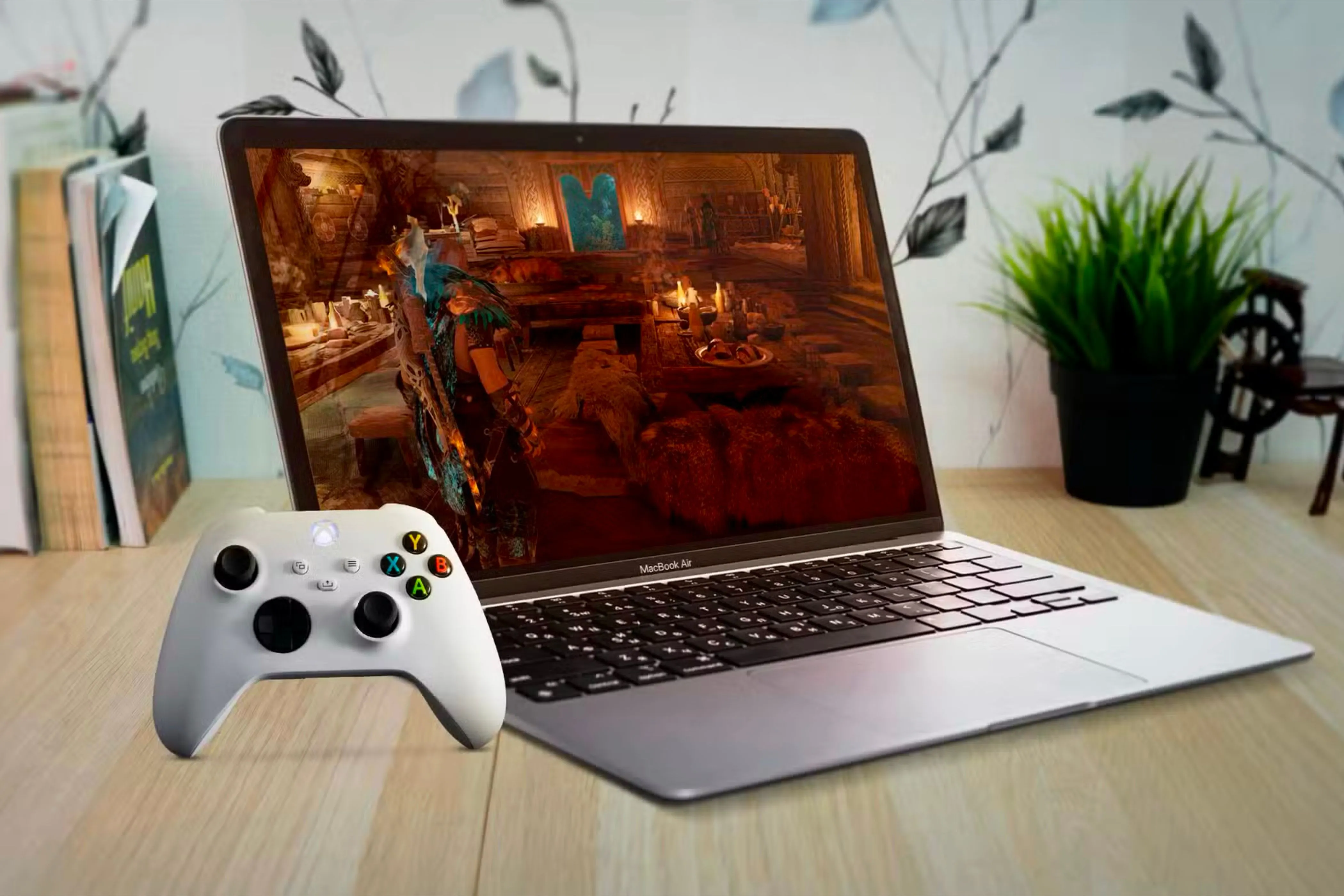 MacBook Air đặt trên bàn gỗ, hiển thị game trên màn hình, với tay cầm Xbox ở gần, minh họa việc chơi game trên Mac.