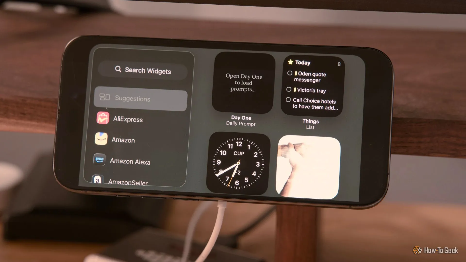 Màn hình hiển thị các widget tùy chỉnh trong chế độ StandBy của iPhone 15 Pro trên giá đỡ kẹp bàn