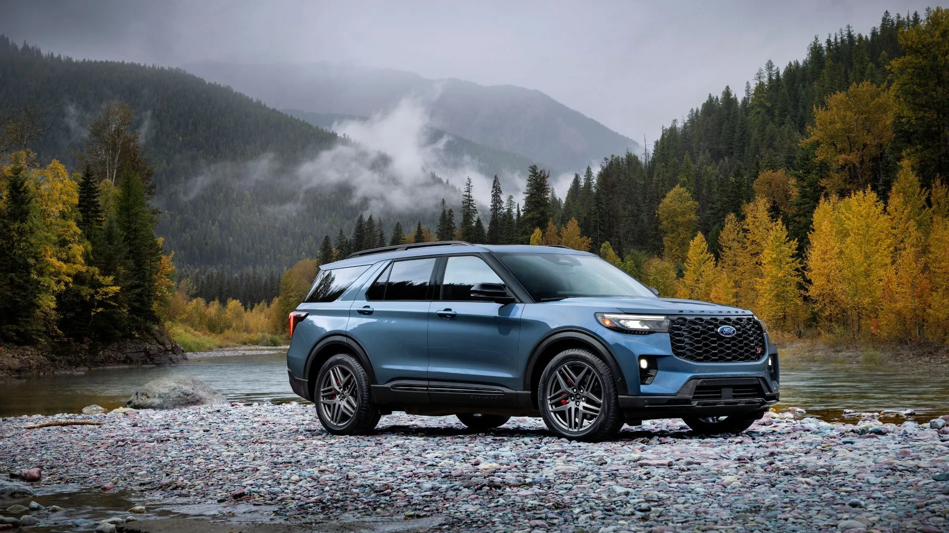 Mặt trước ba phần tư của chiếc Ford Explorer ST 2025 màu xanh đậu trên đá ở núi.