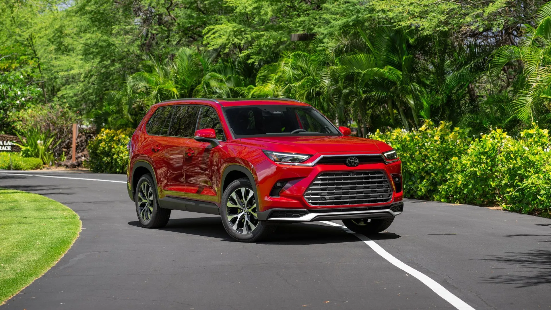 Mẫu SUV Toyota Grand Highlander Hybrid 2025 phiên bản Platinum màu đỏ sang trọng, dừng trên đường phố, minh họa sự cân bằng giữa sức mạnh và hiệu quả nhiên liệu.