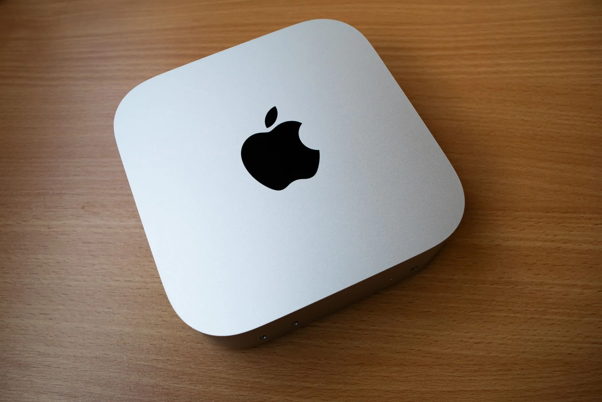 Máy Mac Mini (M4) màu bạc đặt trên bàn gỗ, với thiết kế nhỏ gọn, hiện đại và hiệu năng ổn định.